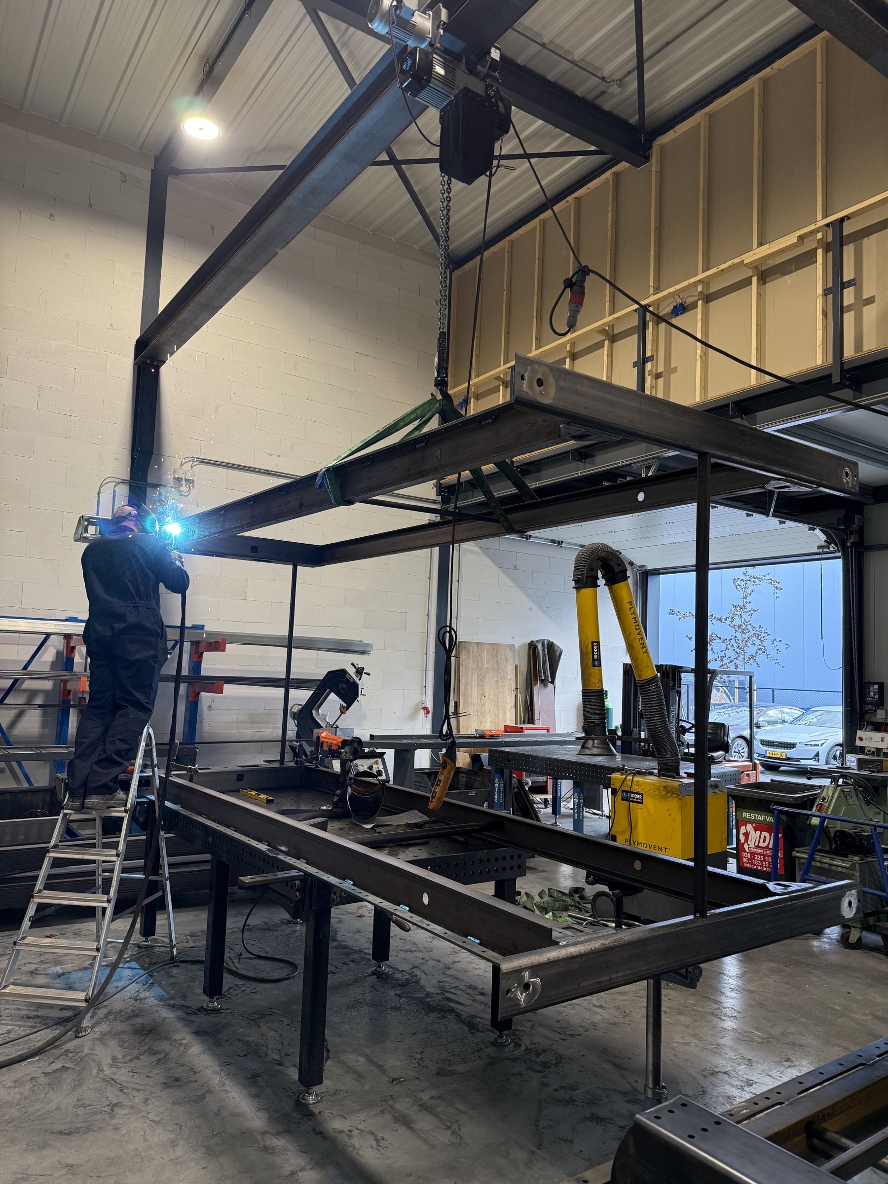 Lassen aan een zware stalen constructie in de werkplaats