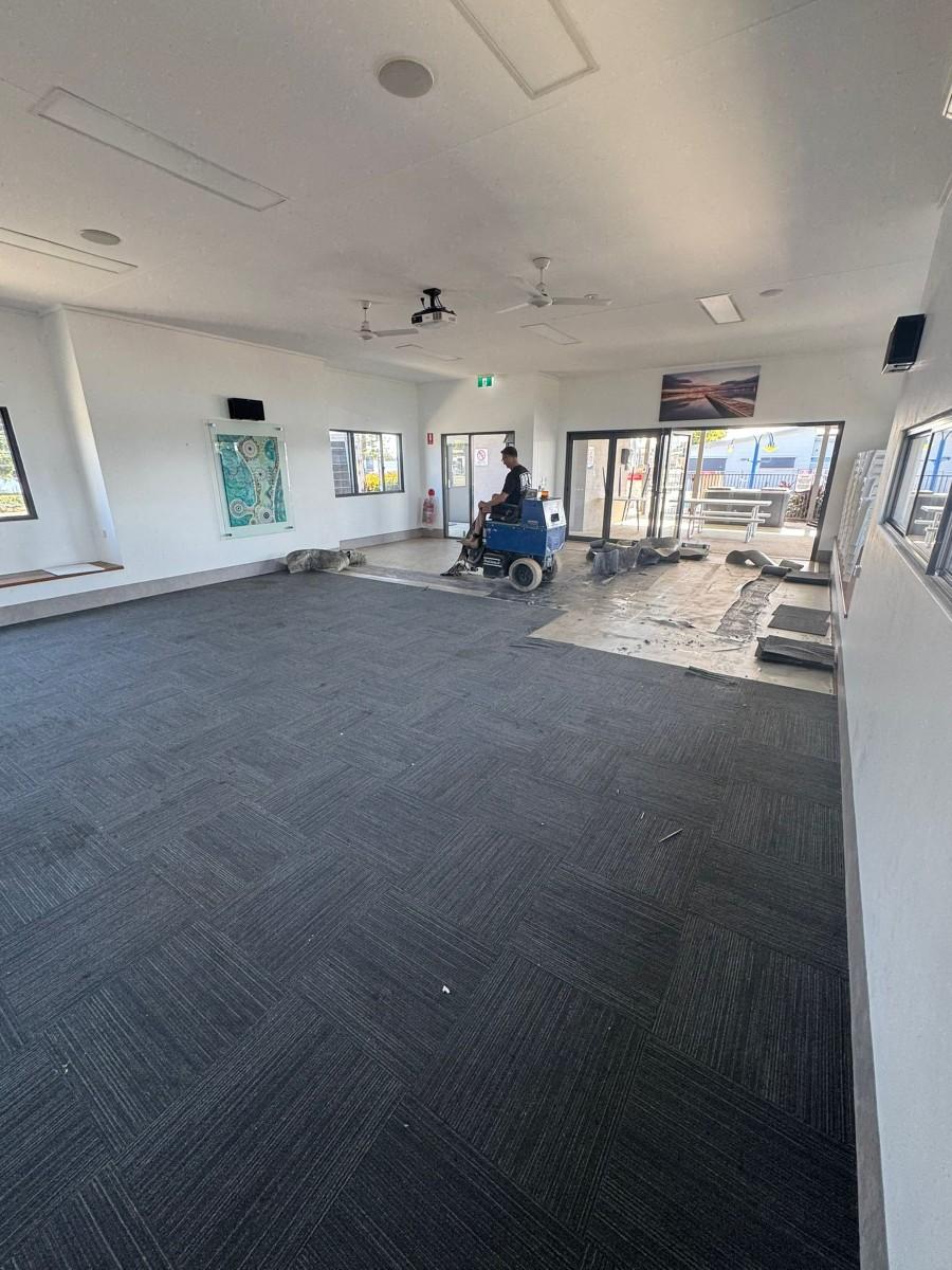 Carpet tile being lifted from a commercial concrete floor