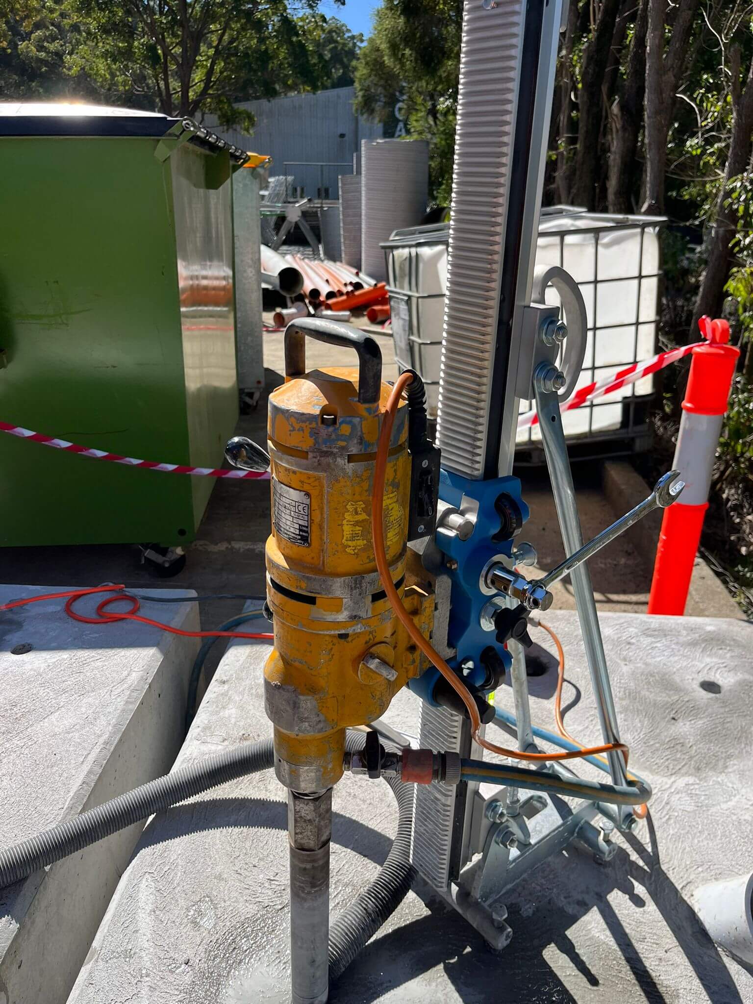 Core drill rig mounted on a stand, drilling into a concrete slab