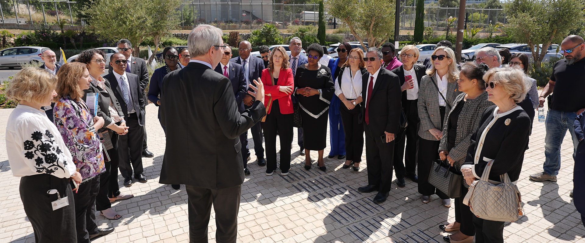 A speaker addresses delegation participants during an outdoor briefing.