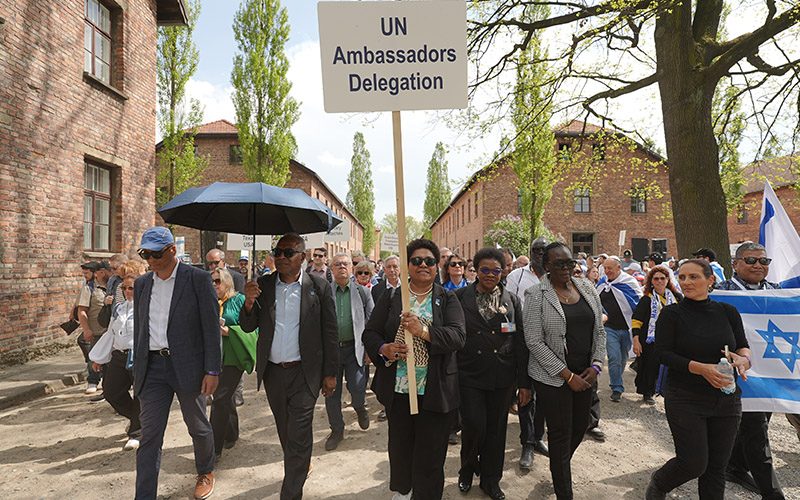A group walks beneath a sign reading ‘UN Ambassadors Delegation.’