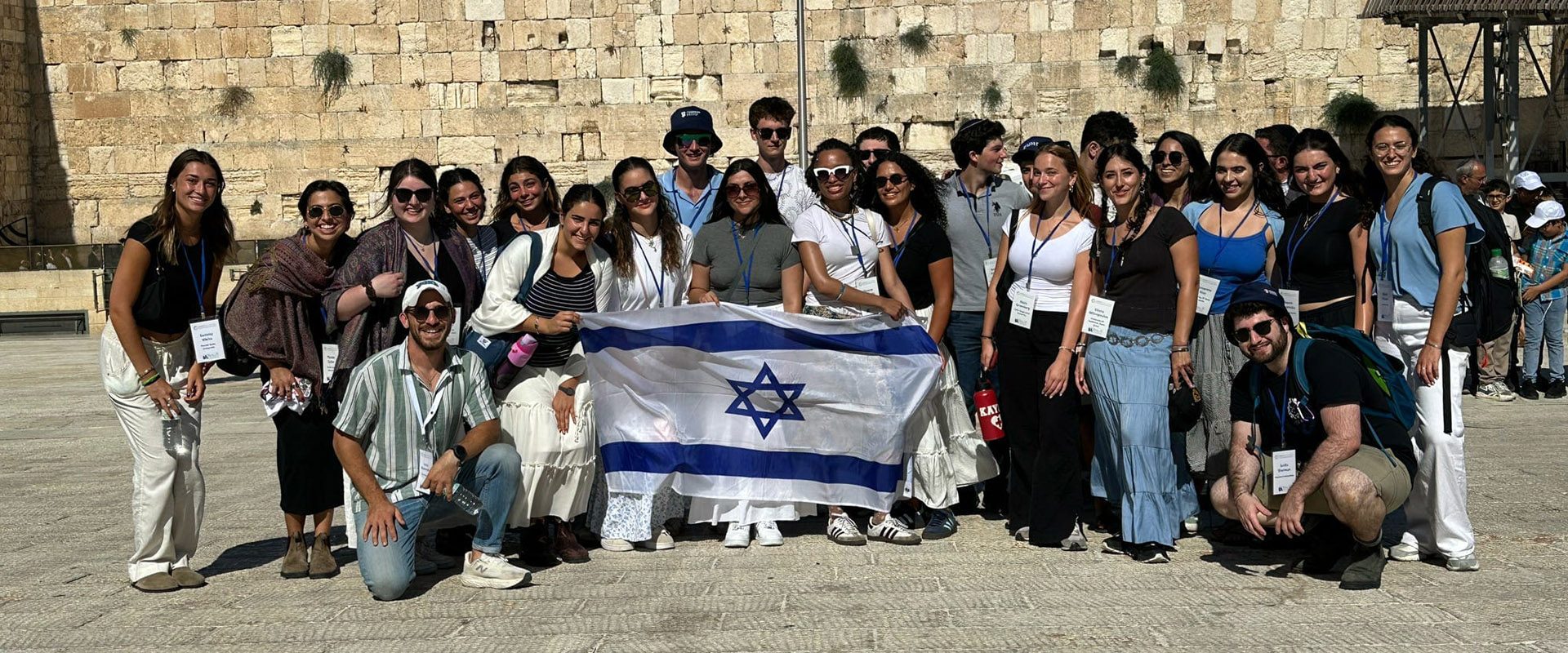 Delegation participants pose with an Israeli flag at the Western Wall.