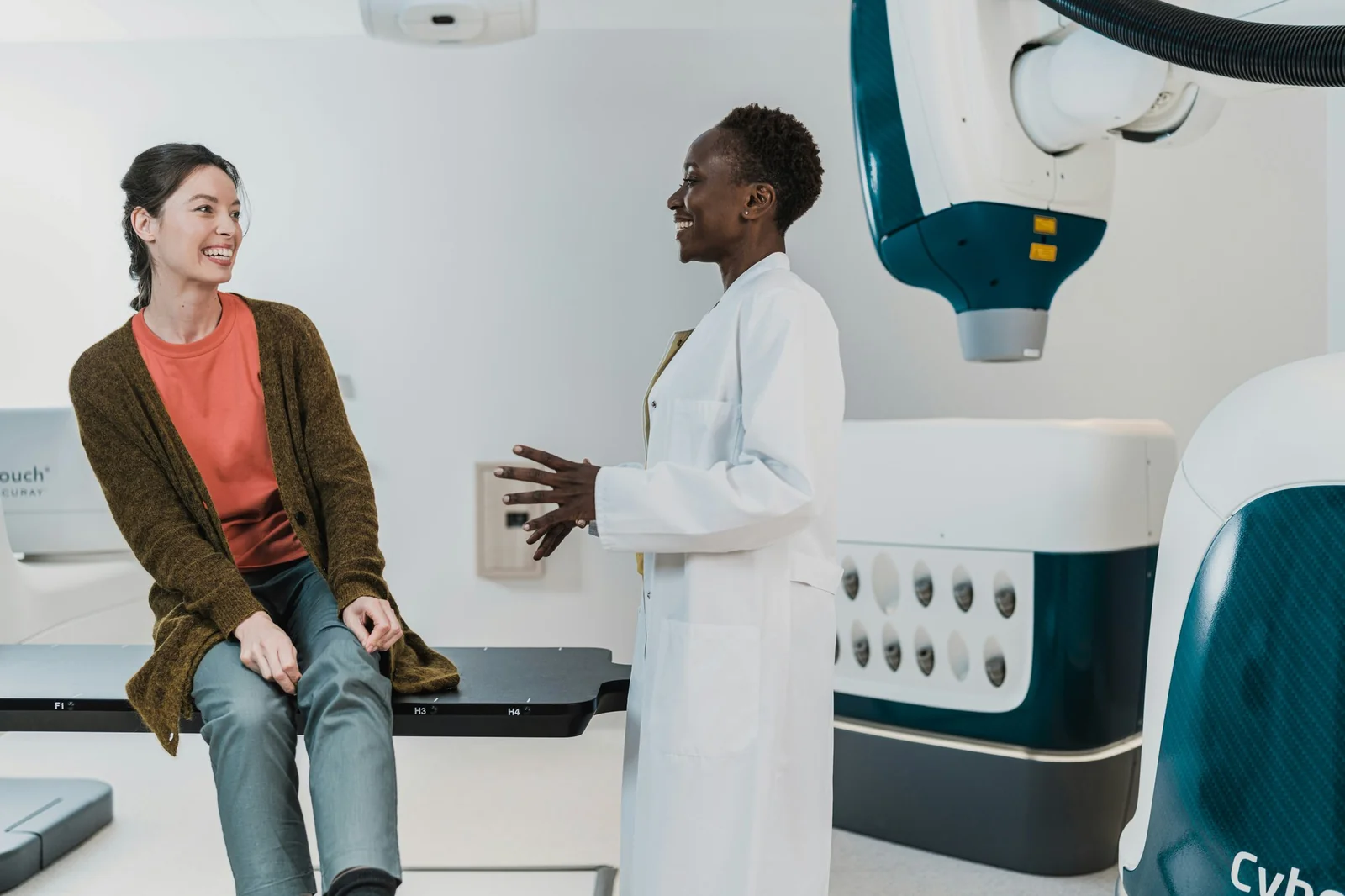 Une médecin échange avec une patiente assise sur une table de traitement