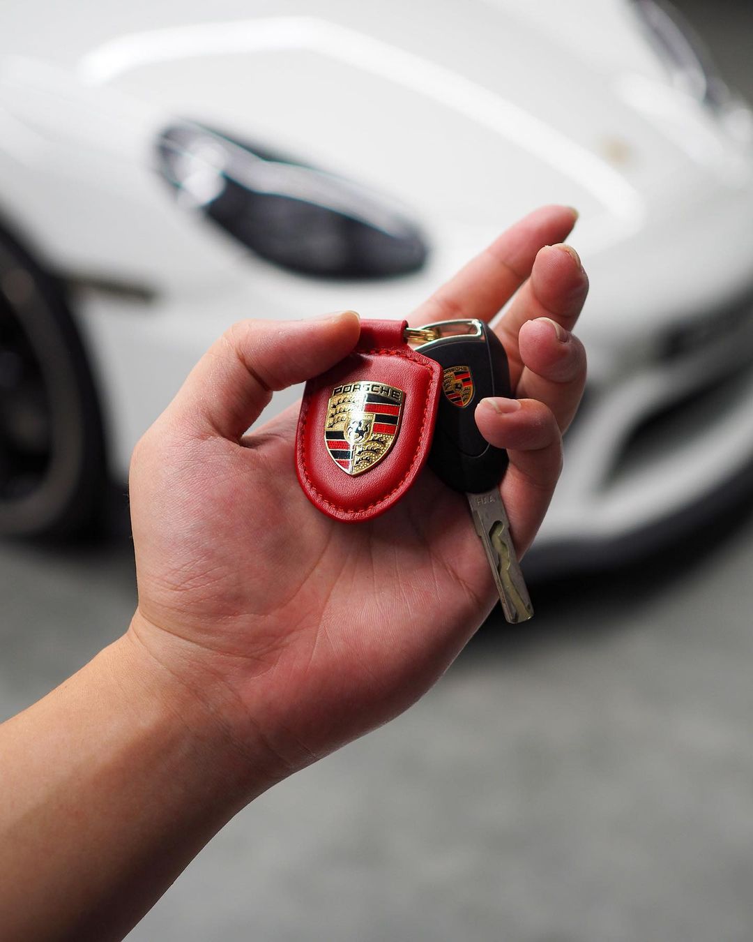 Close-up of a hand holding a luxurious car key inside United Motoring showroom, symbolizing the premium car ownership experience.