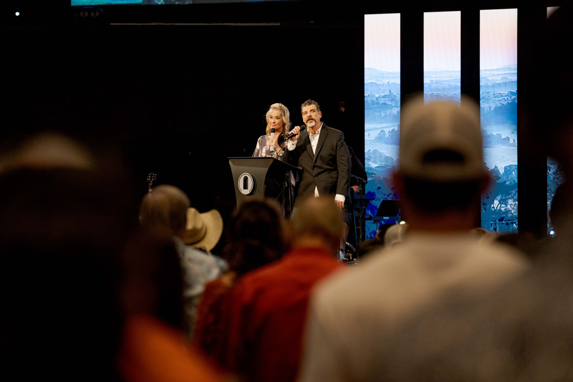 Two speakers on stage, viewed from within the congregation