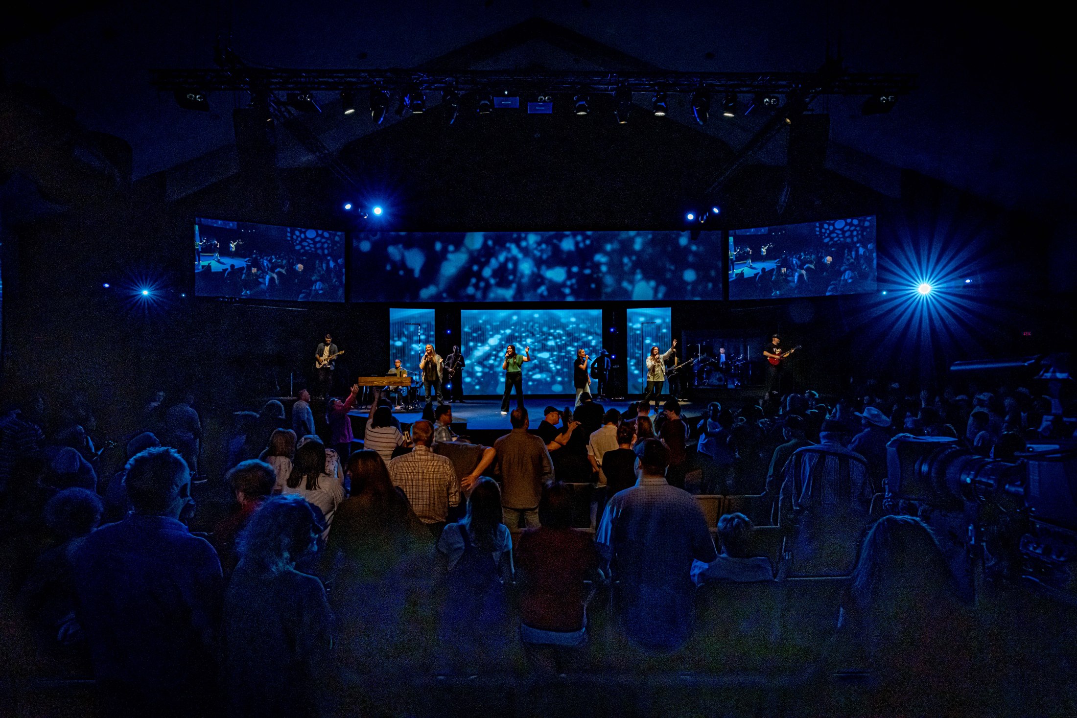 A wide view of the congregation and blue-lit stage