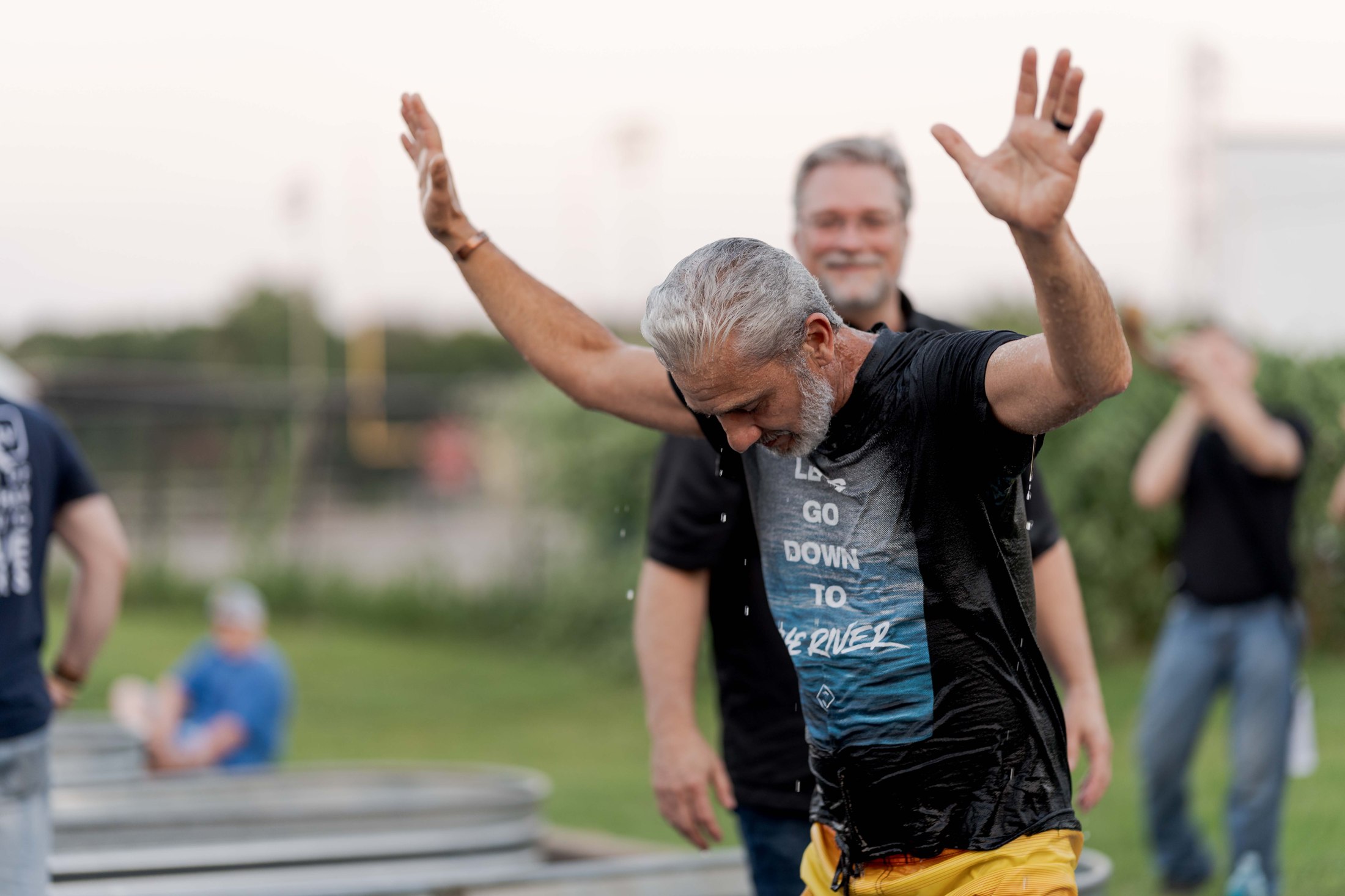 A man raising his hands beside an outdoor baptism tank
