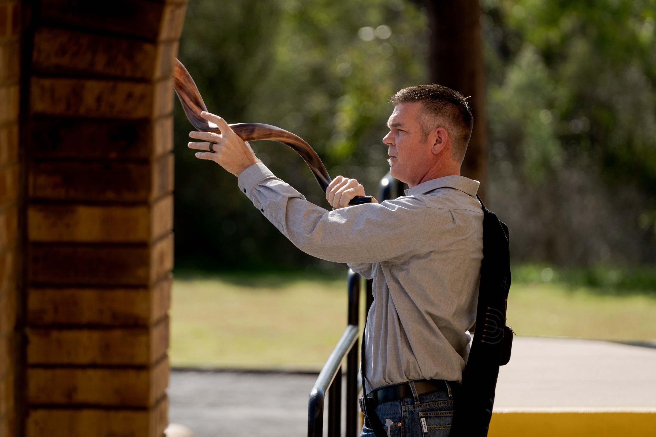 A speaker addressing an outdoor gathering in warm daylight