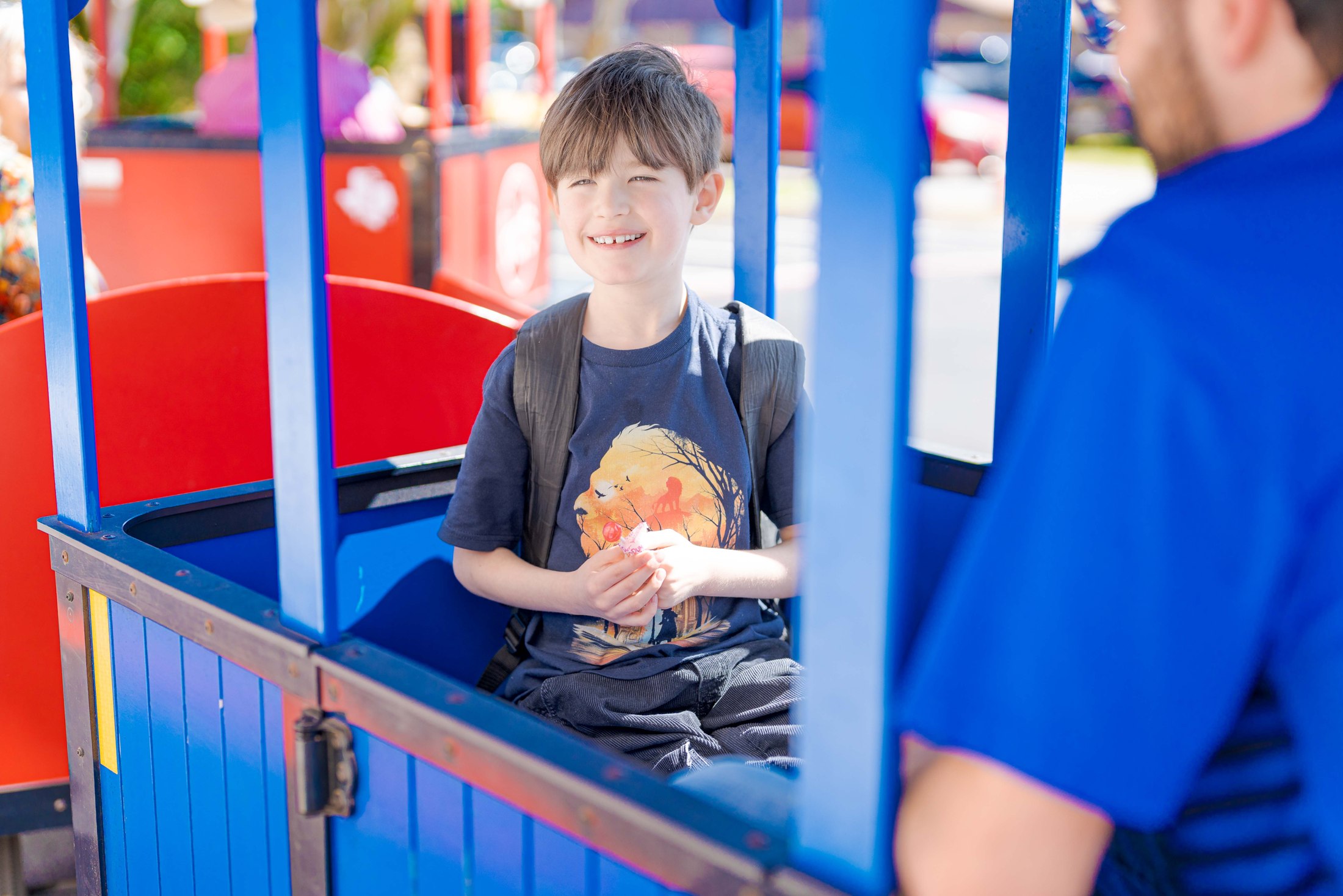 A smiling child riding in a colorful visitor tram