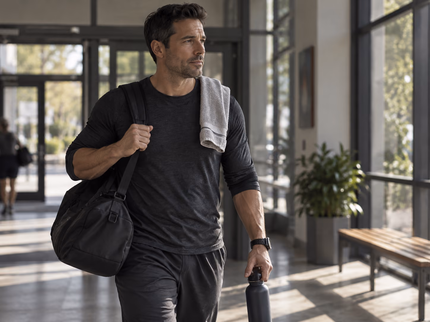 First responder carrying a gym bag and water bottle through a bright facility