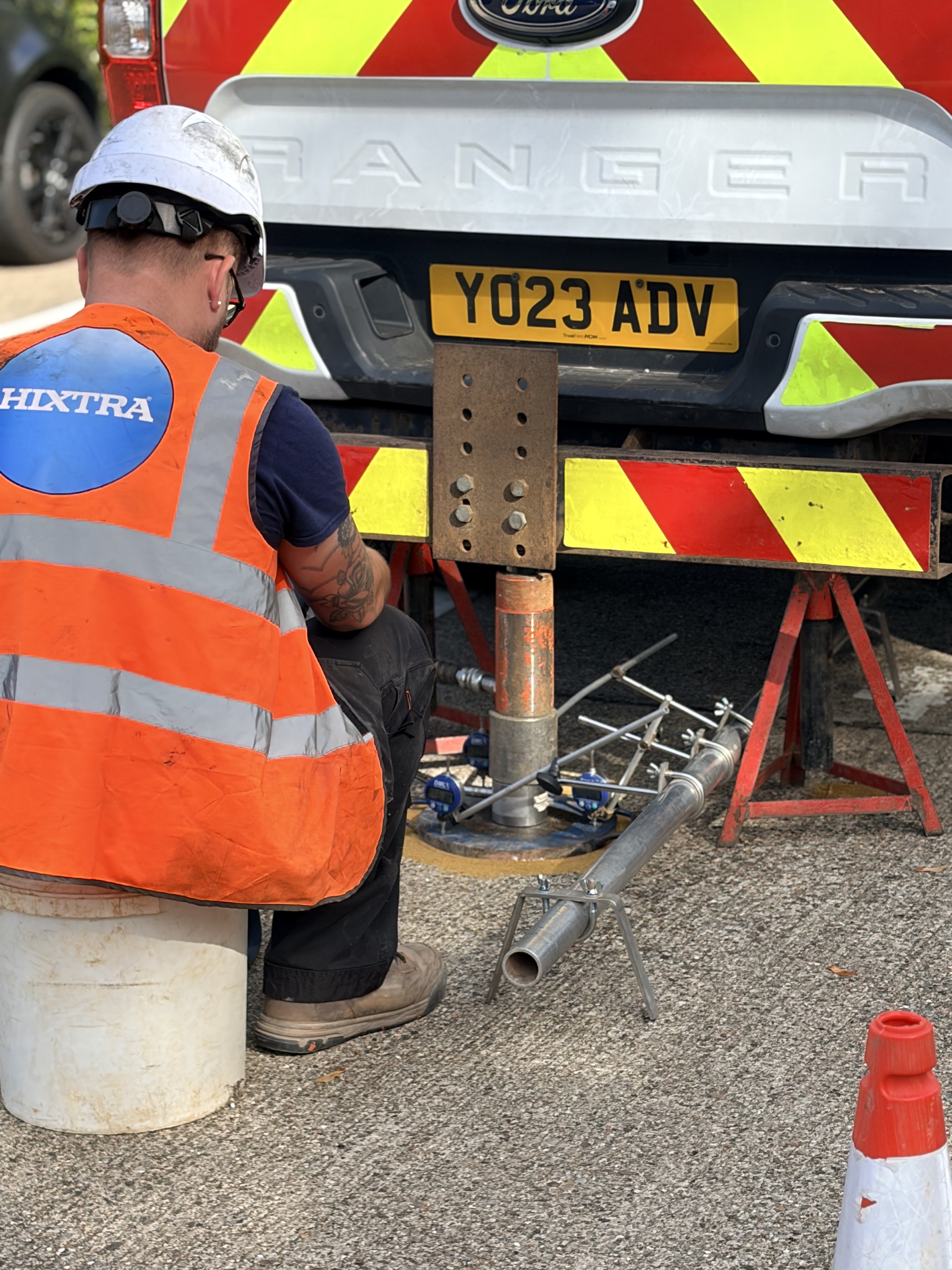 Hixtra technician carrying out in-situ ground testing with a rig under a van