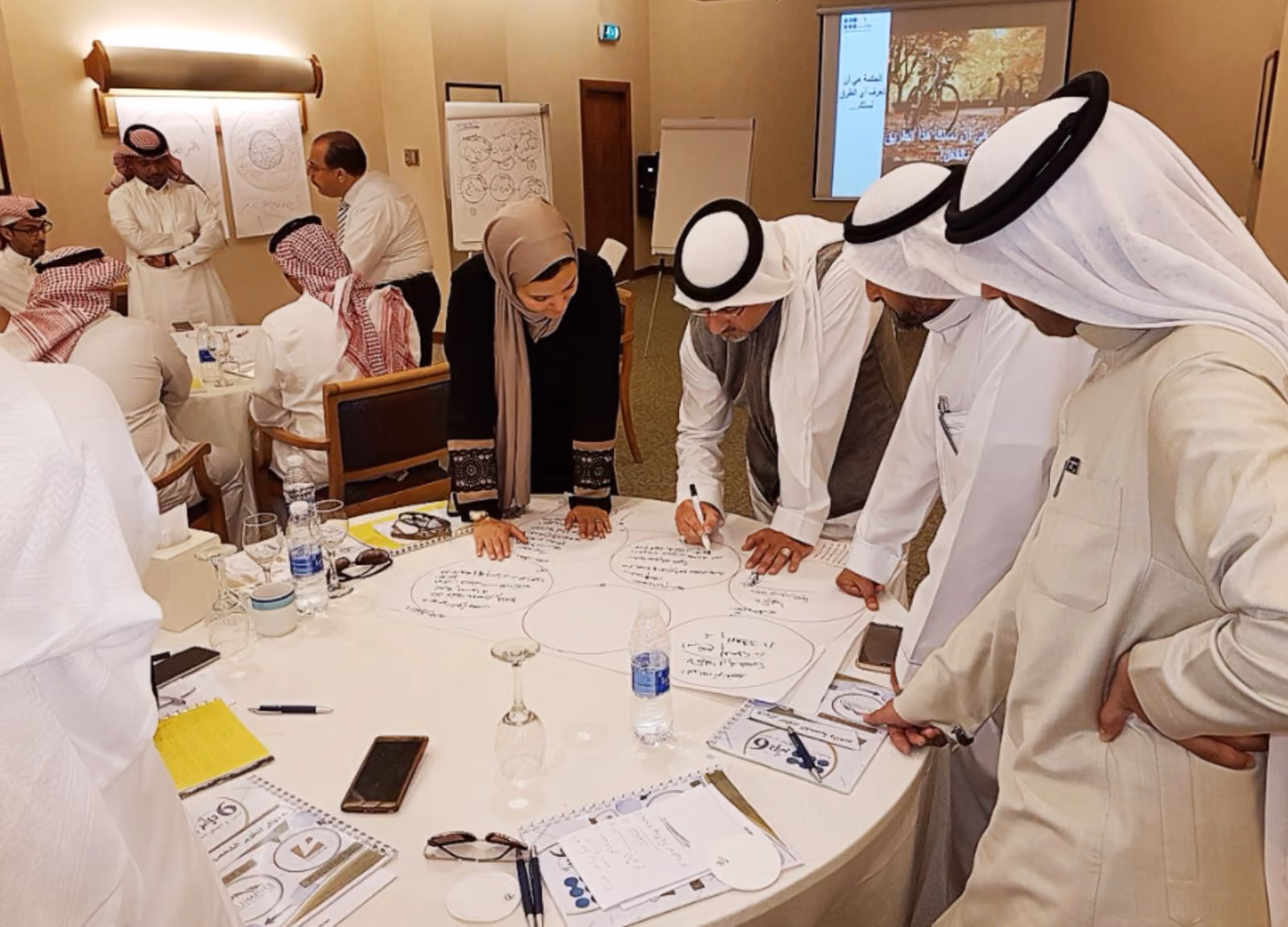 A workshop group working together on a large Six Circles sheet laid across a round table.