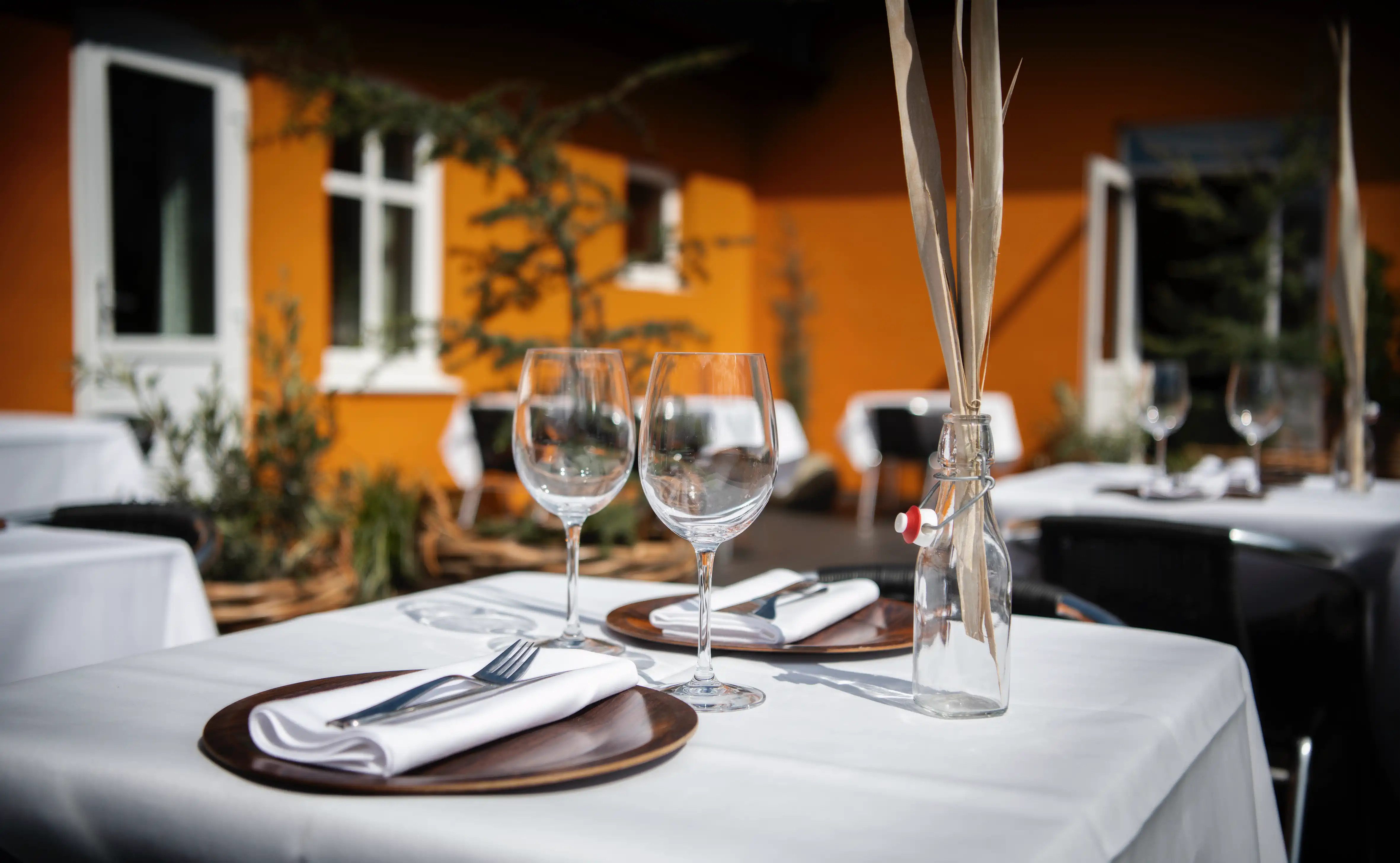 Dækket bord med vinglas og hvide servietter på Gammel Høvers terrasse.