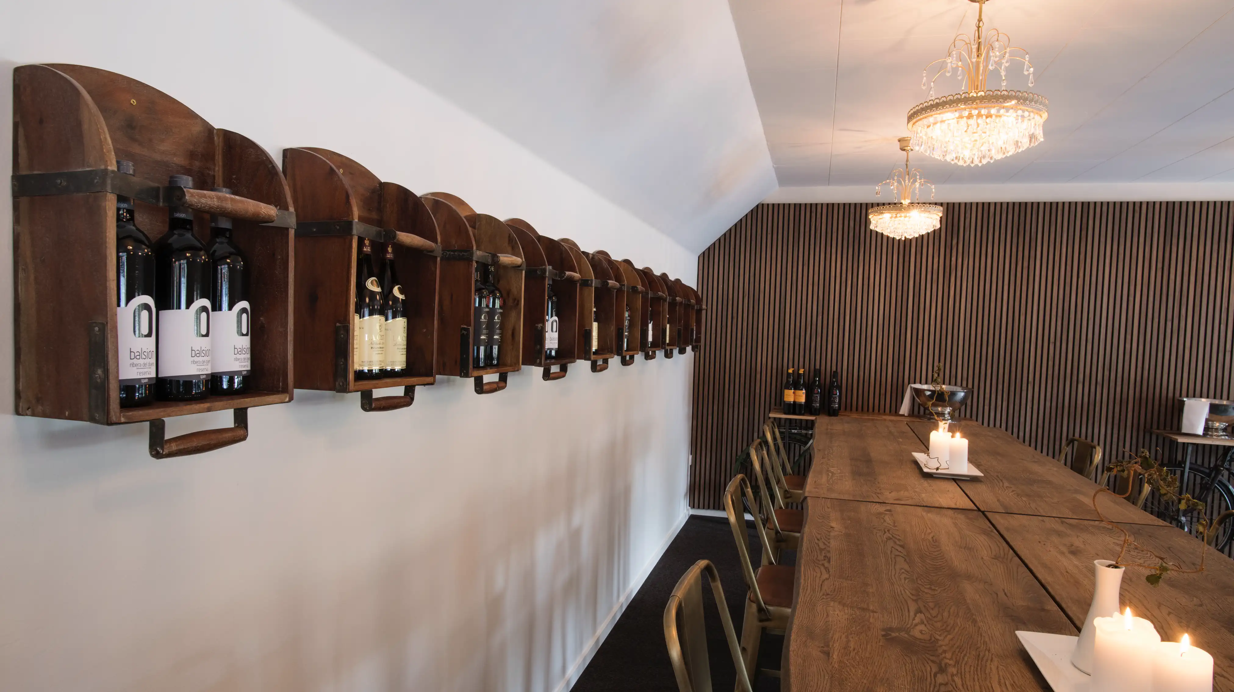 Langbord med vinflasker på væggen i vinbaren på Venge Kloster.