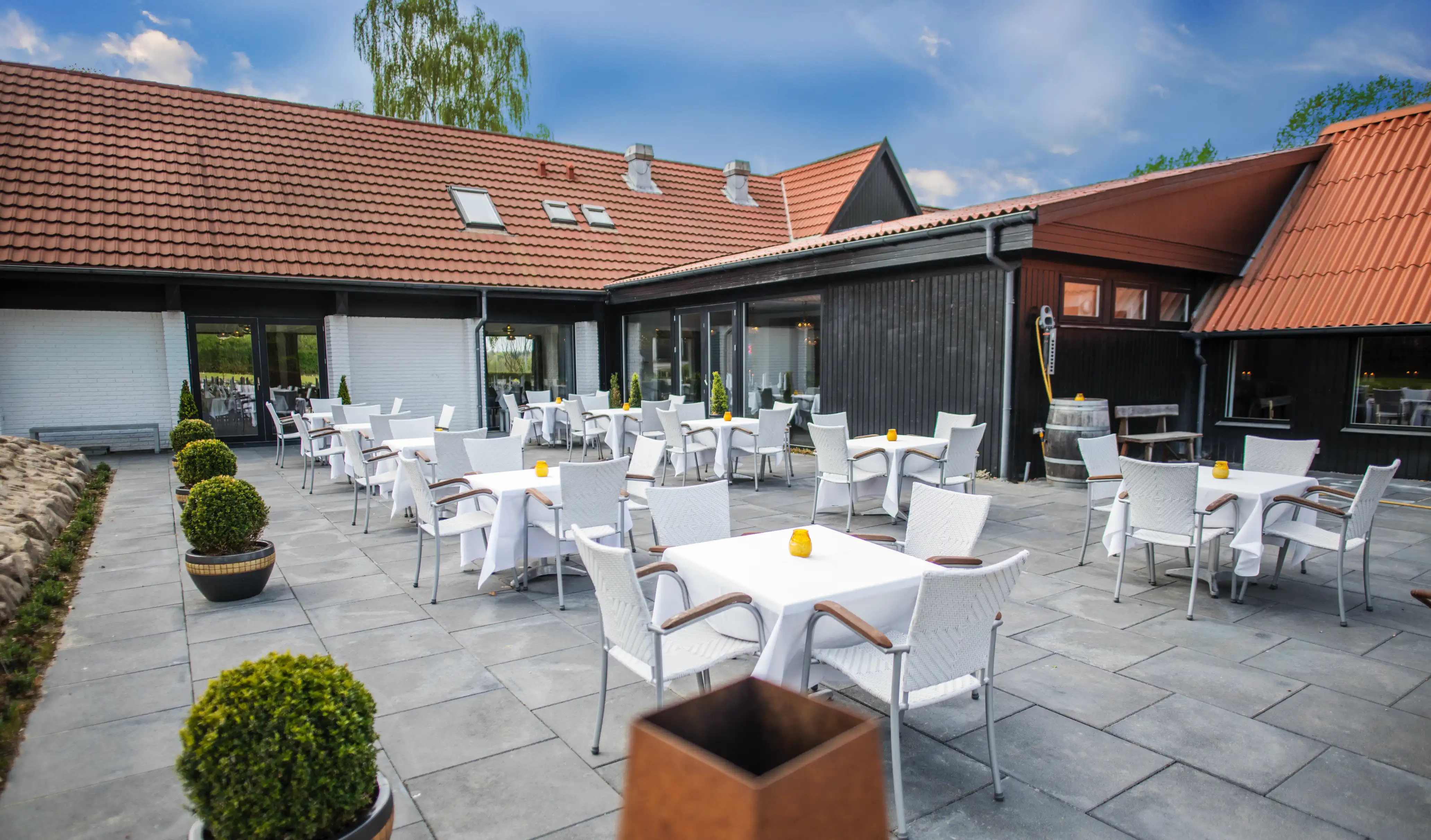 Terrassen på Venge Kloster med dækkede borde foran restauranten.