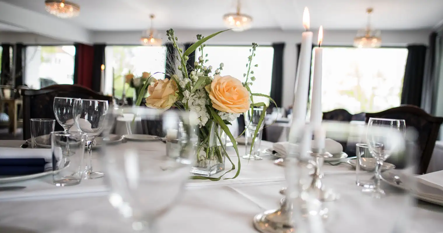 Festbord med en gul rose, vinglas og hvide servietter.