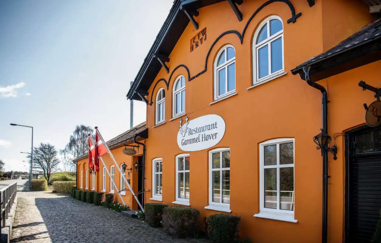 Gammel Høvers gule facade med buede vinduer og restaurantens skilt.