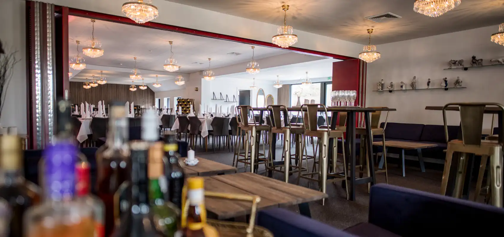 Vinbar på Venge Kloster med høje borde og flasker i forgrunden.
