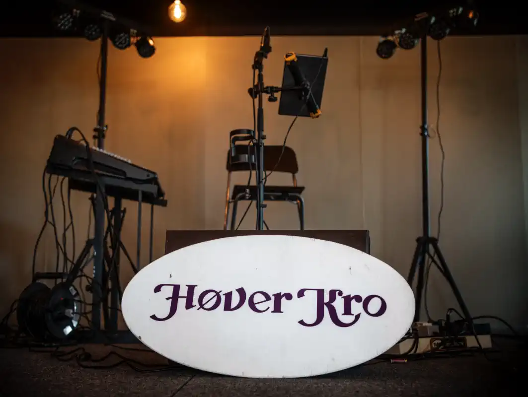 Musikscene med keyboard, mikrofoner og skiltet Høver Kro.