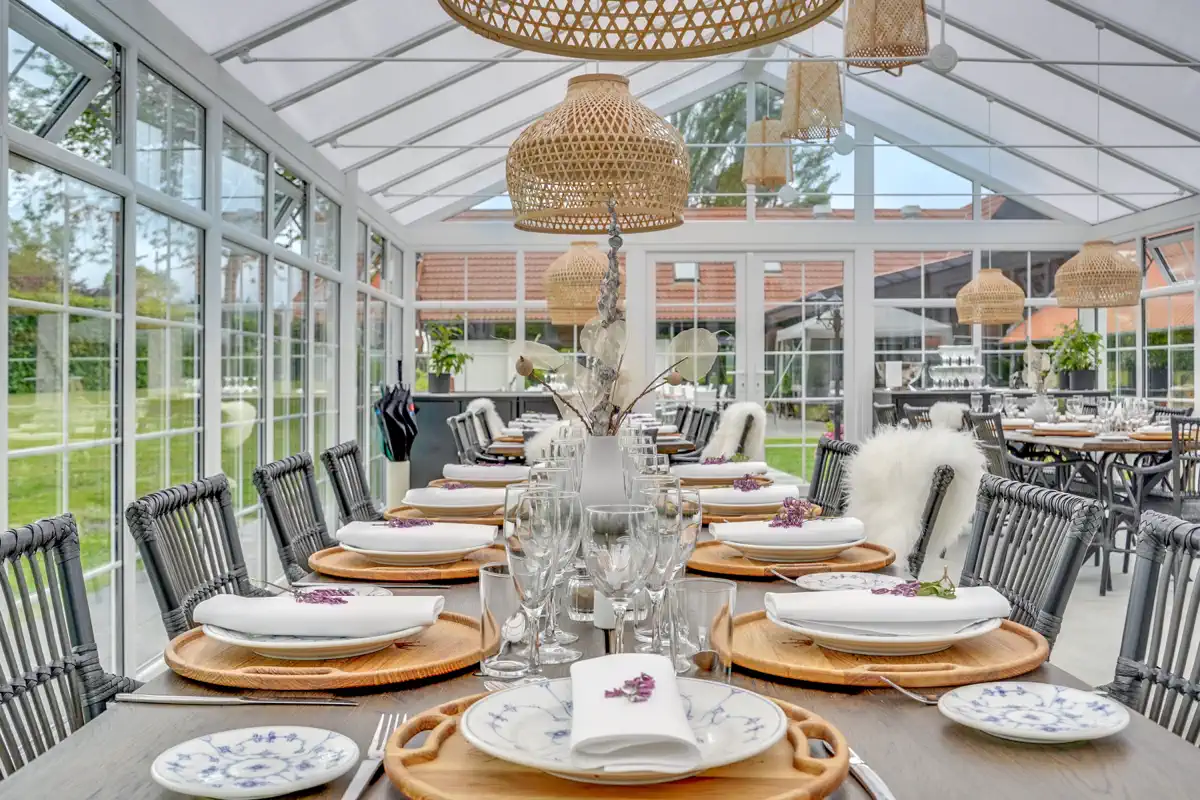 Dækket festbord med tallerkener og vinglas i Orangeriet på Venge Kloster.