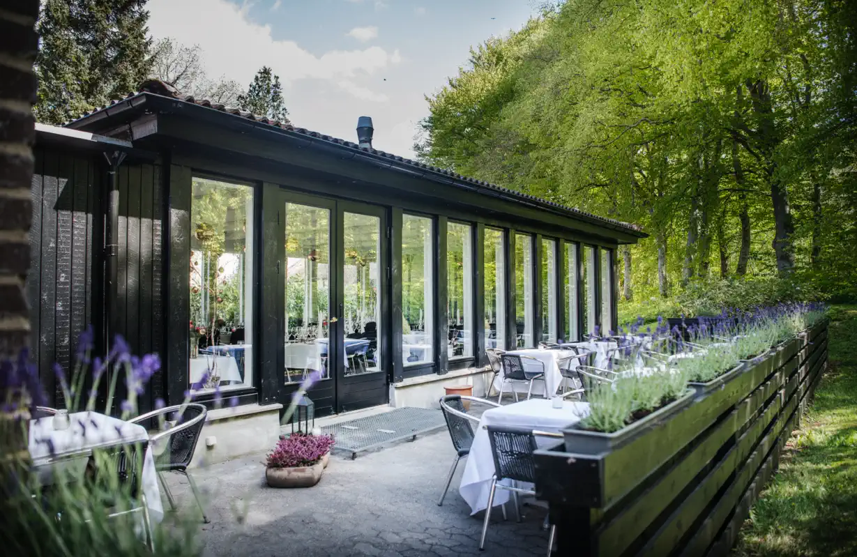 Glassalen på Lilleringskov set udefra med dækkede borde på terrassen.