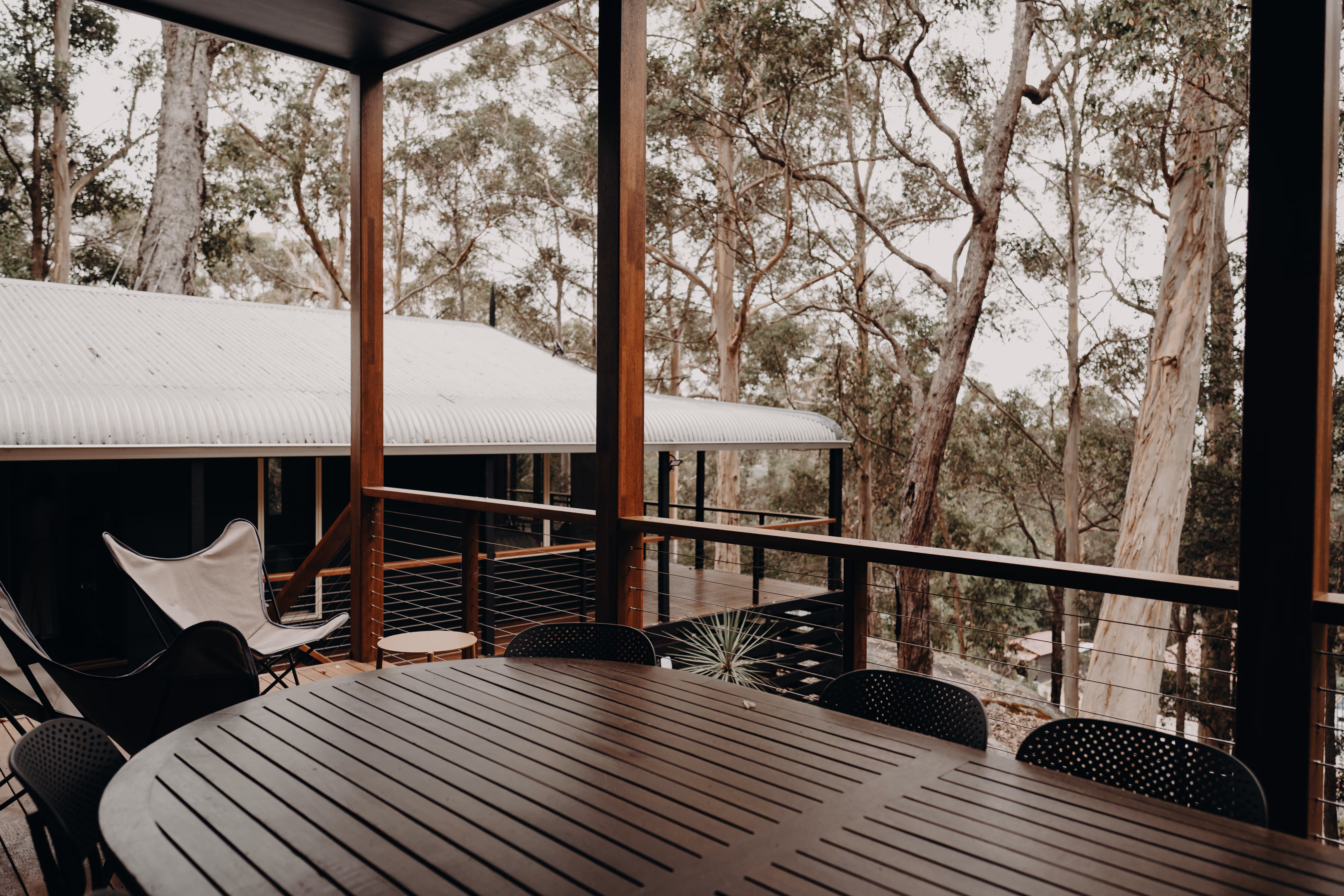 Covered outdoor dining deck among karri trees on a renovated Denmark home