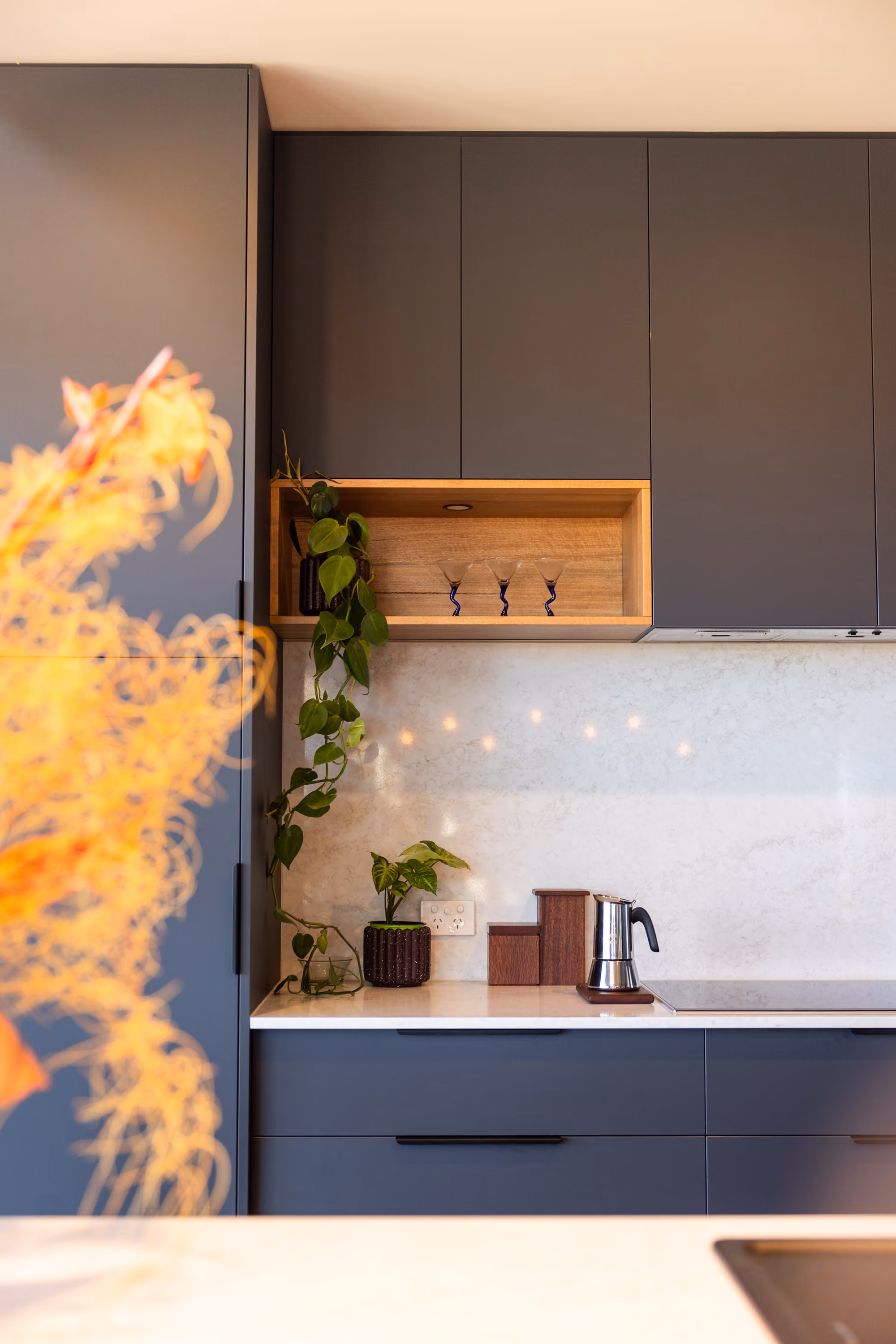 Charcoal kitchen cabinetry and stone splashback in a finished custom home