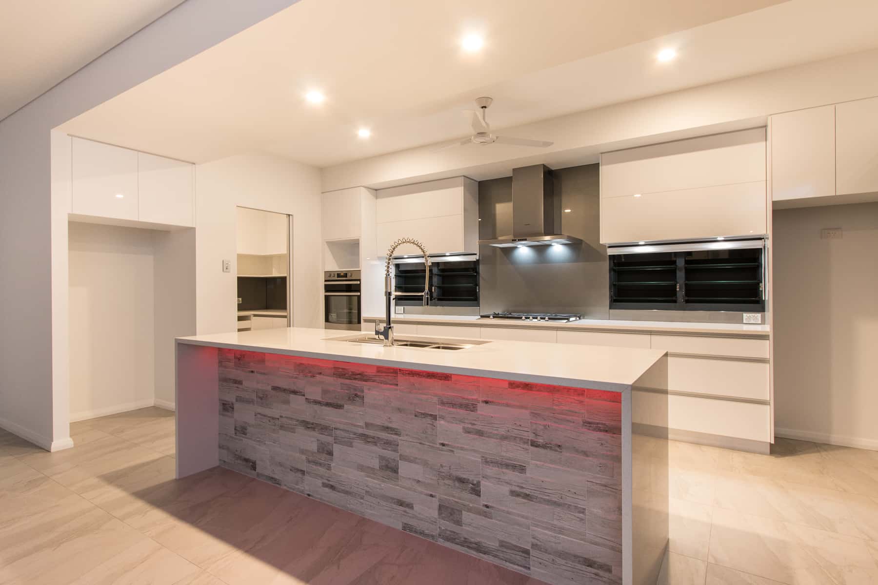 White gloss kitchen with a timber-look clad island in an earlier home built by Michael Smyth
