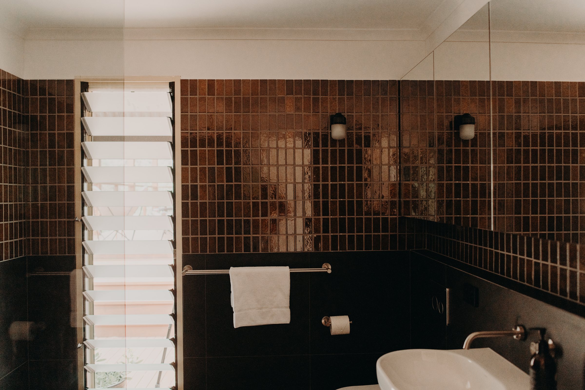 Renovated bathroom with amber mosaic tiles, charcoal tiling and a tall louvre window in Denmark, WA