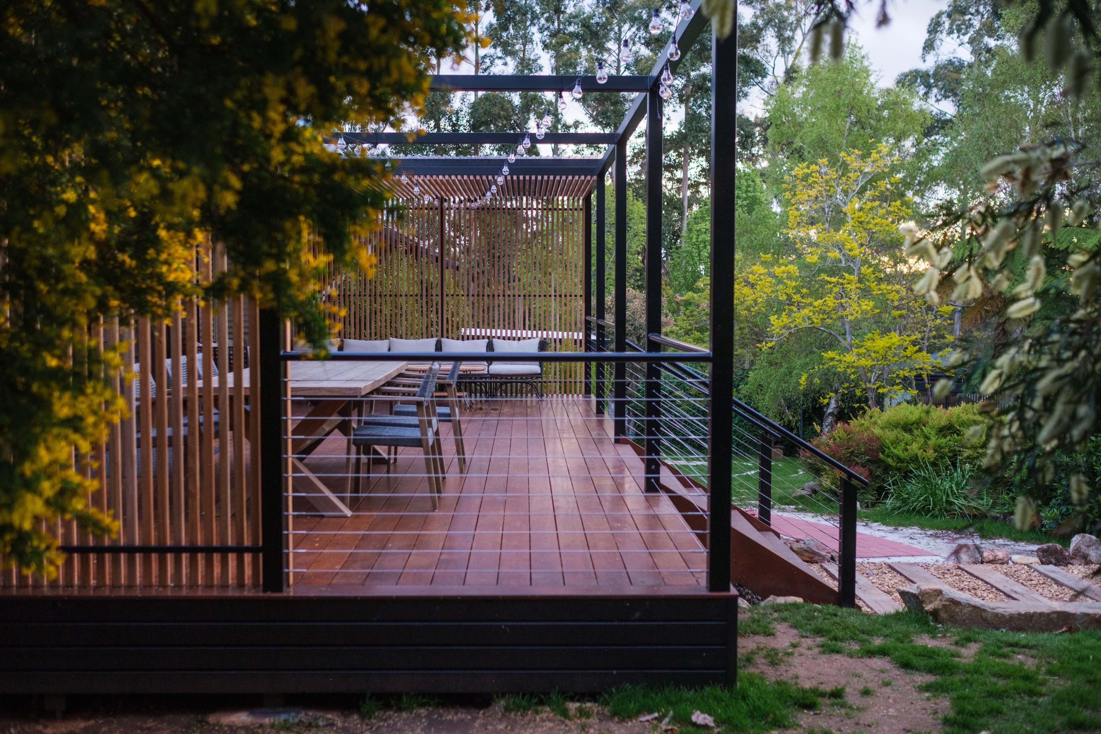 Raised deck with timber stairs stepping down to a garden path on a sloping block