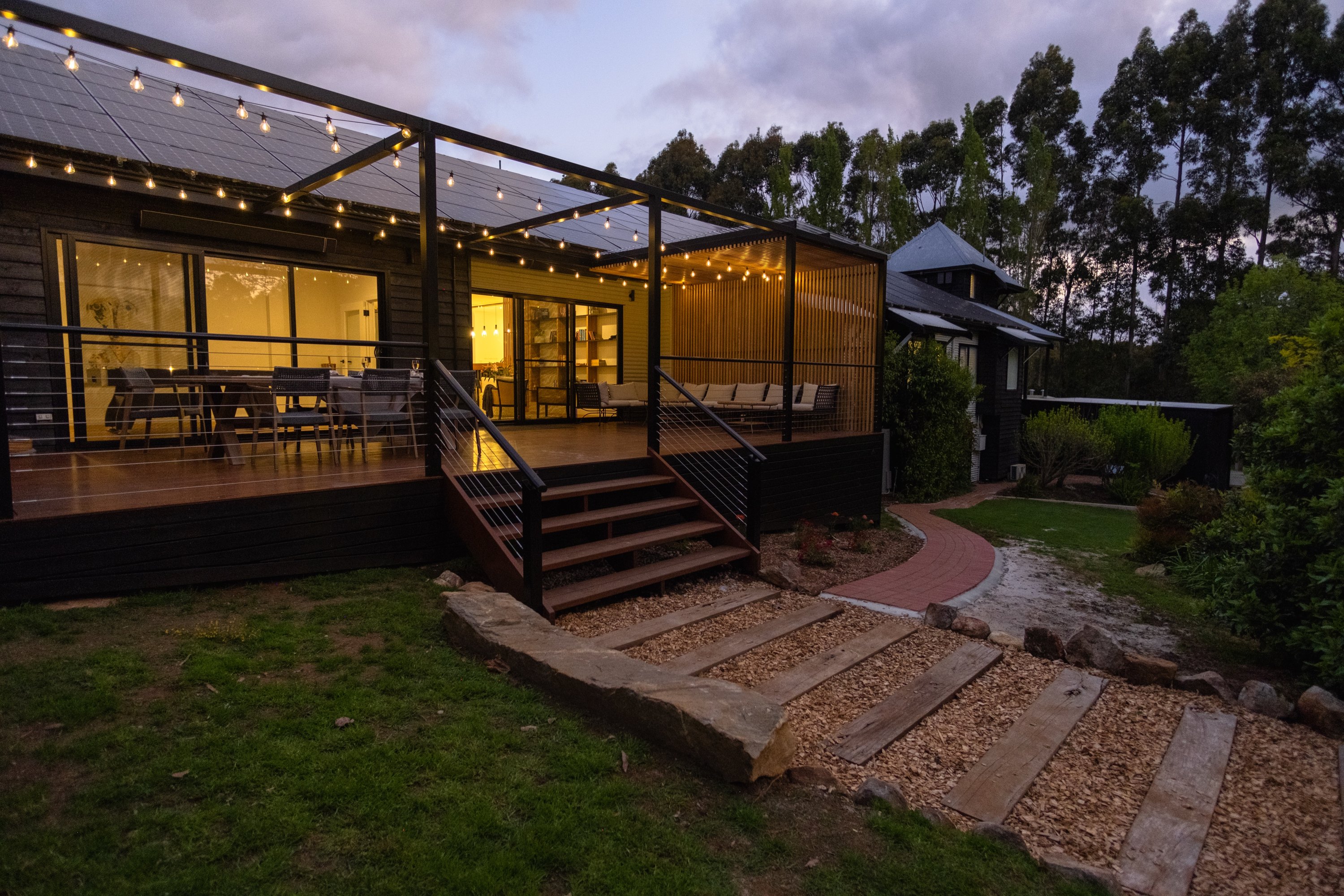 Timber stairs and a sleeper-step gravel path leading up to a deck at dusk