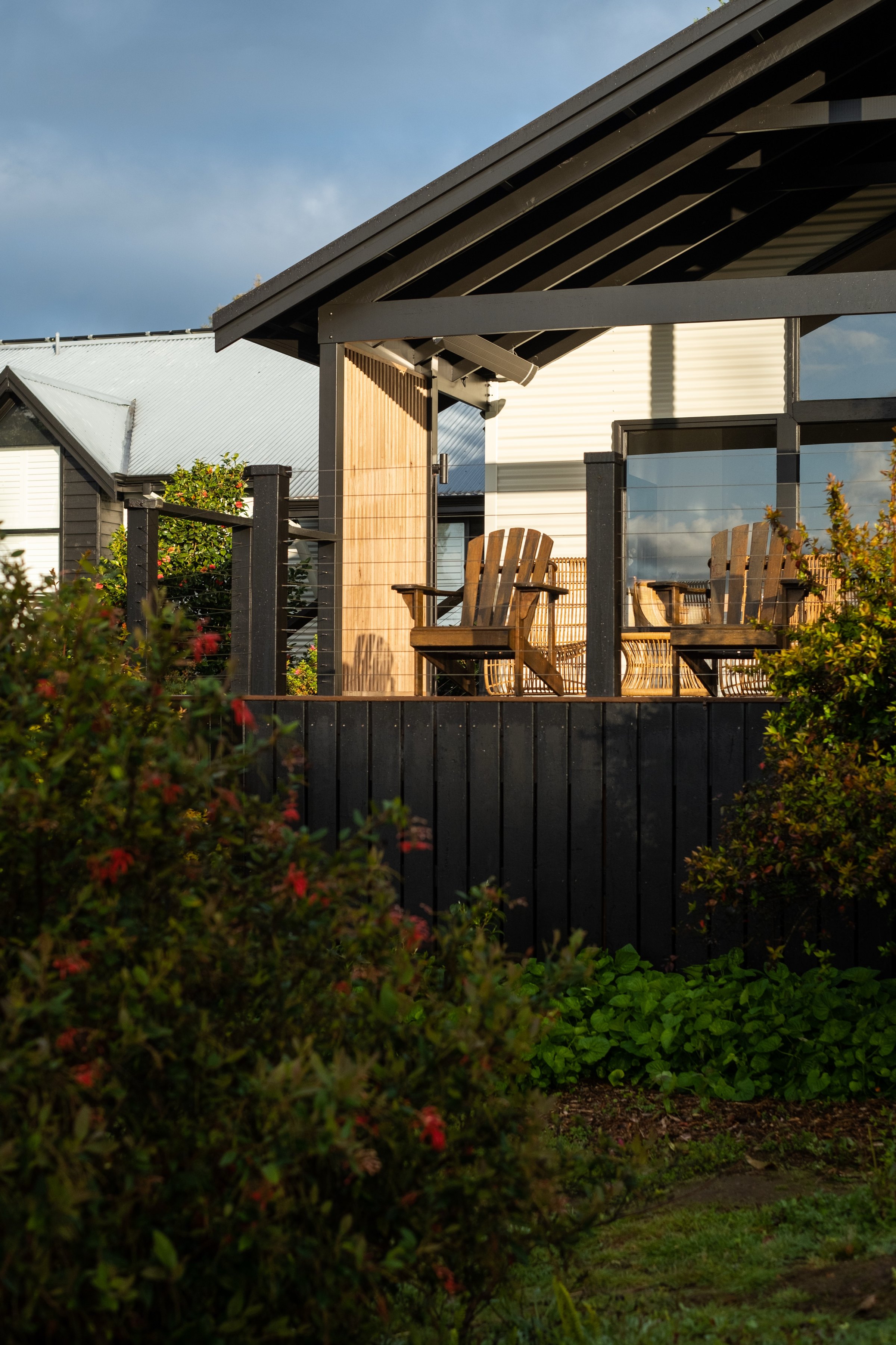 Two timber chairs on a verandah framed by flowering grevillea in the Great Southern