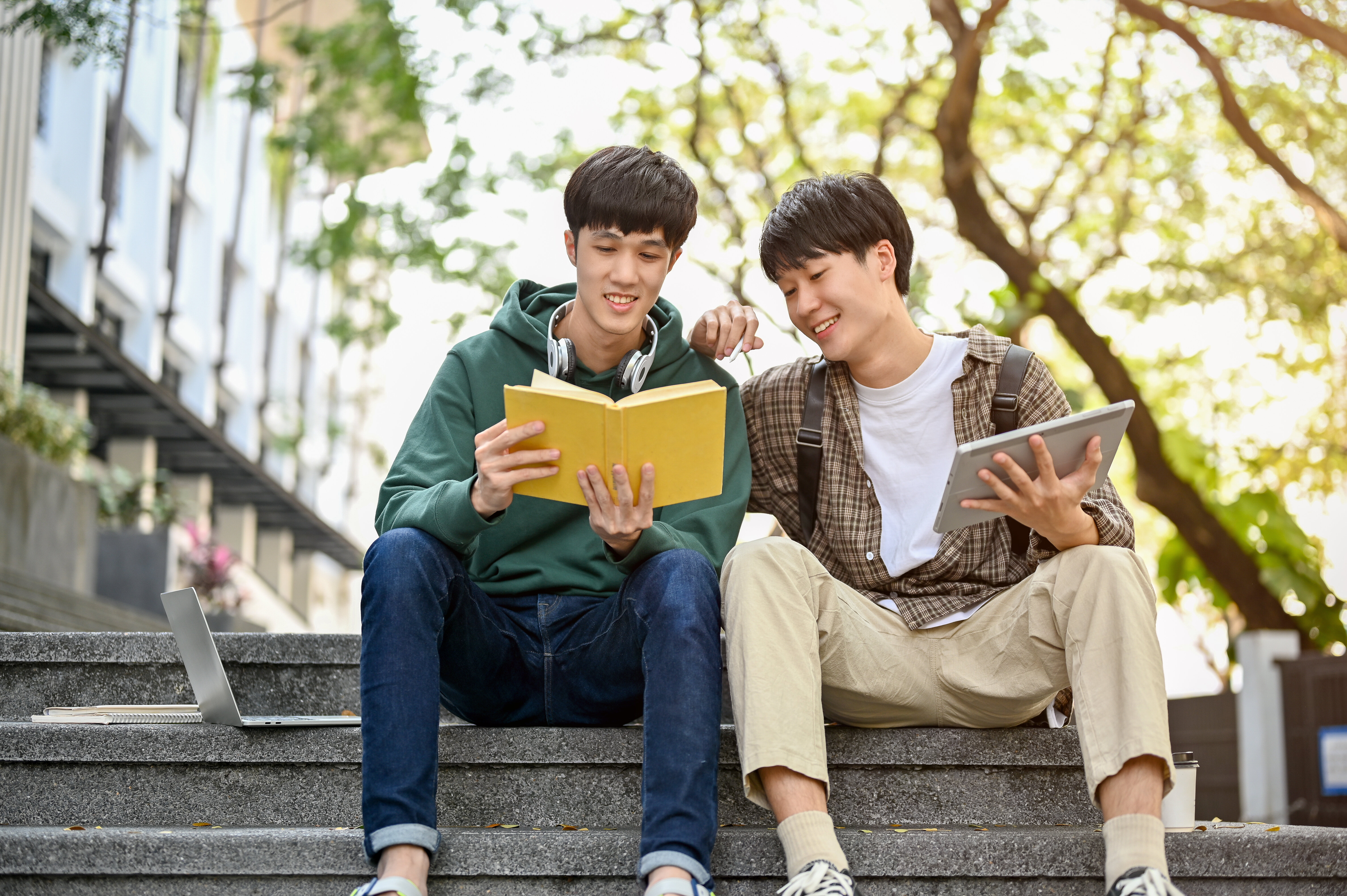 Two guys sitting on stairs with book stock image