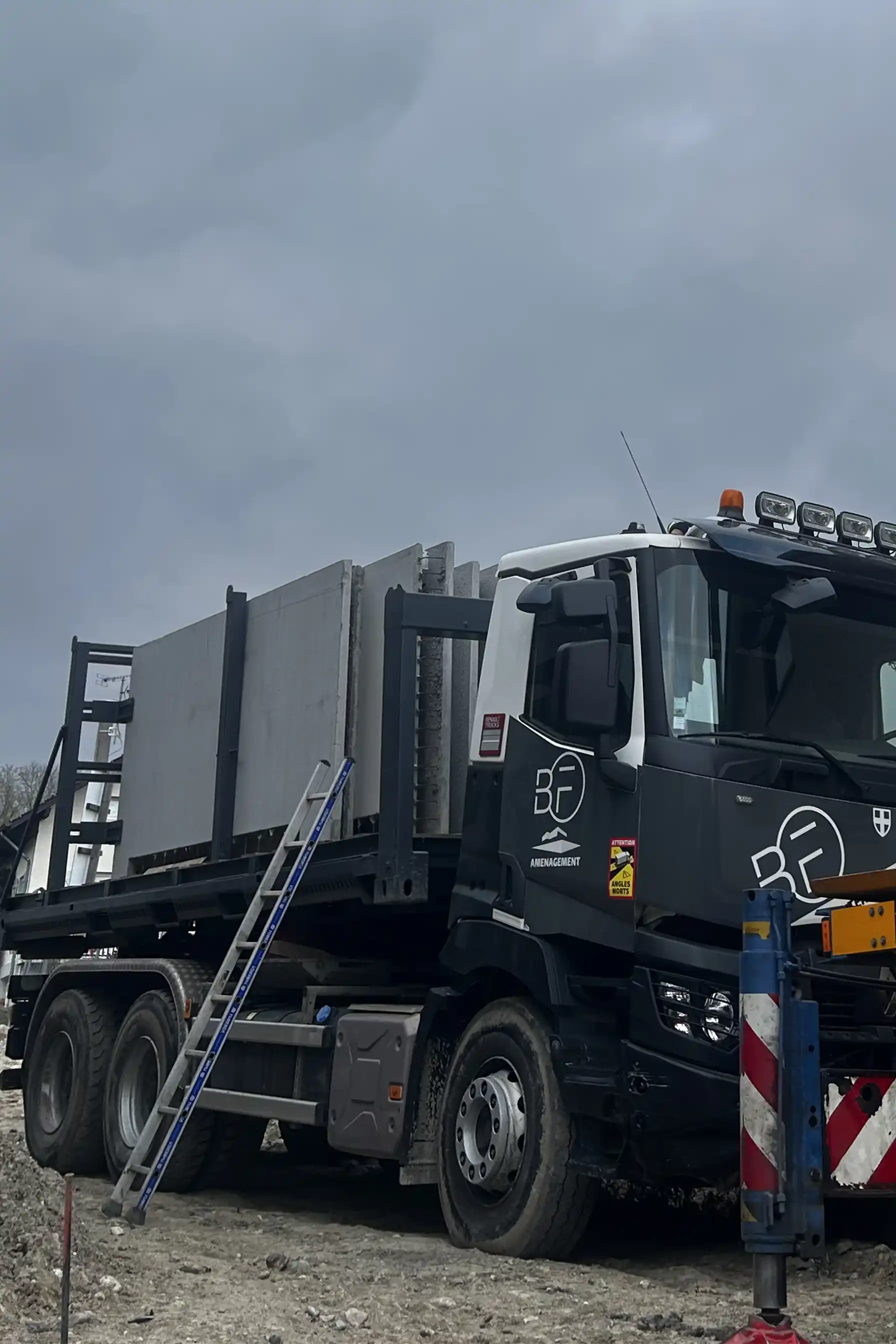un camion équipé d'un plateau ampliroll qui transporte des murs à la vericale