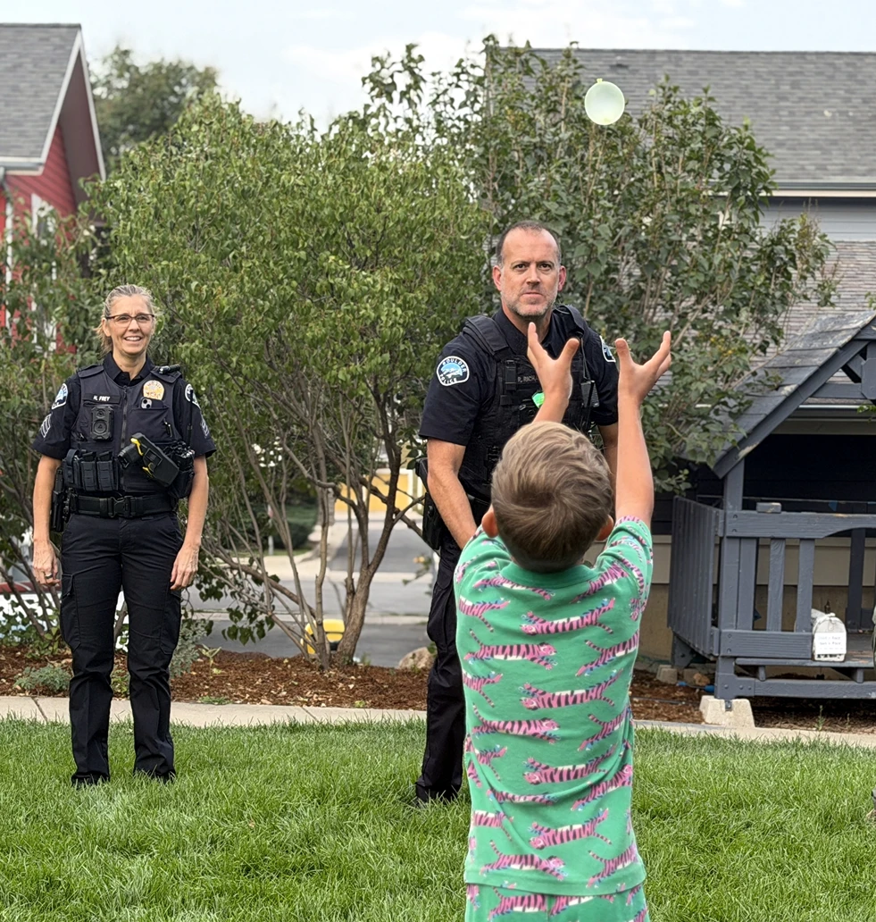 A Boulder police officer tosses a water balloon with a child at a neighborhood event.