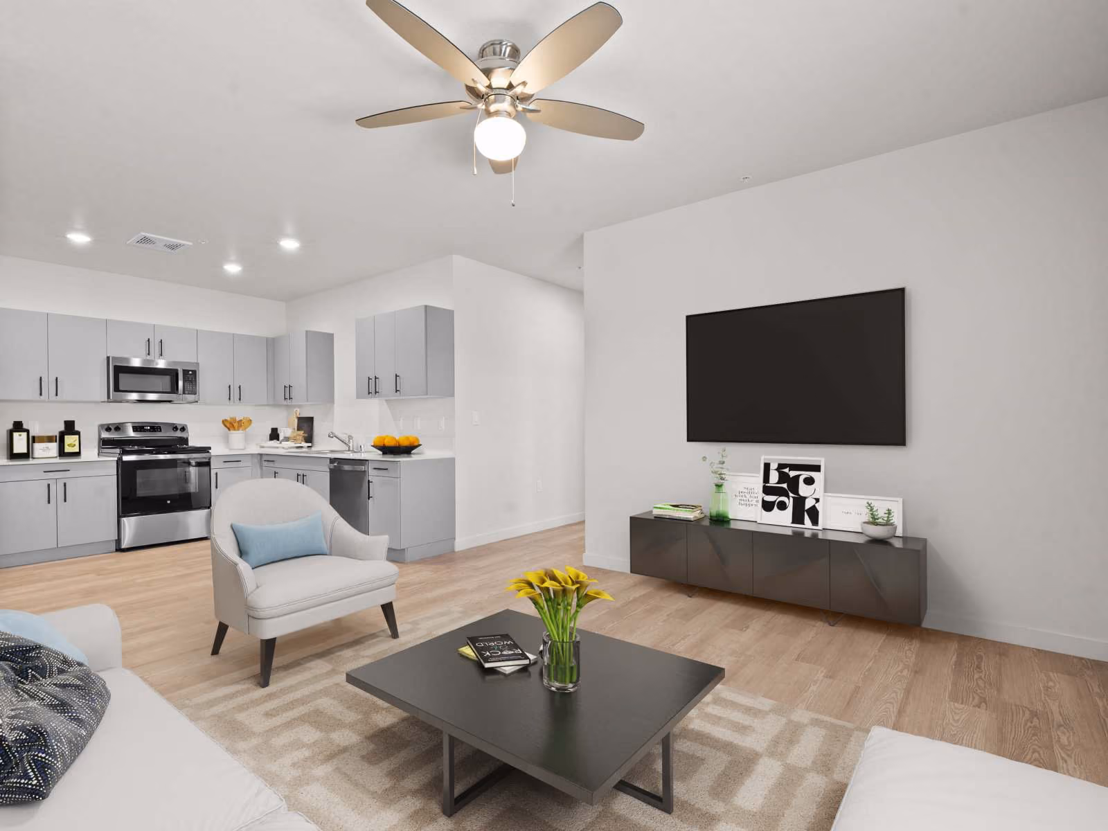 Virtually staged living area with sofa, tv, and coffee table and view of kitchen 