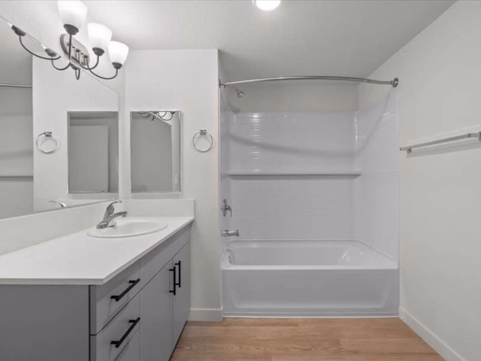 Bathroom with gray cabinets, vanity and shower tub combo