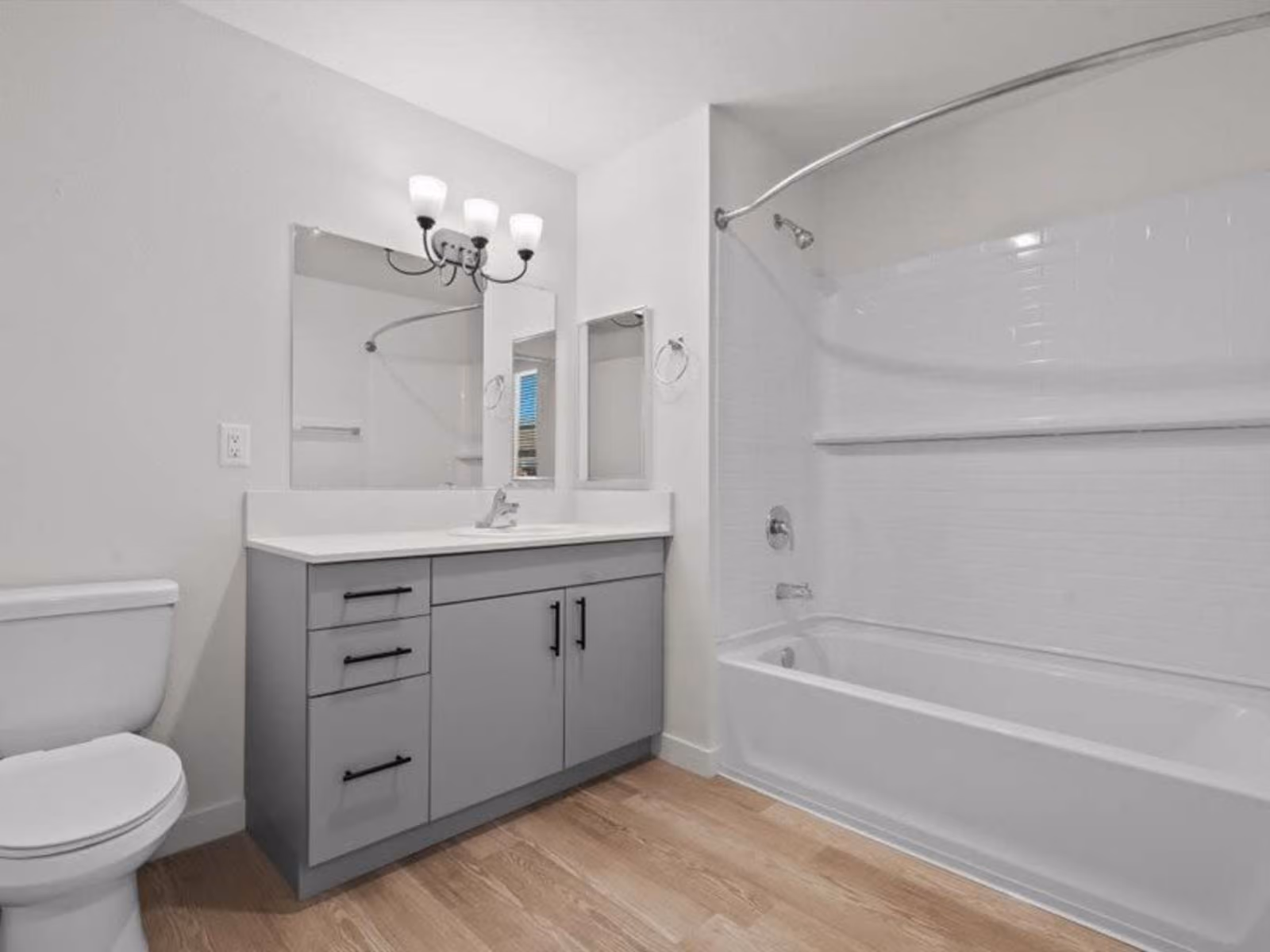 Bathroom with gray cabinets, vanity and shower tub combo
