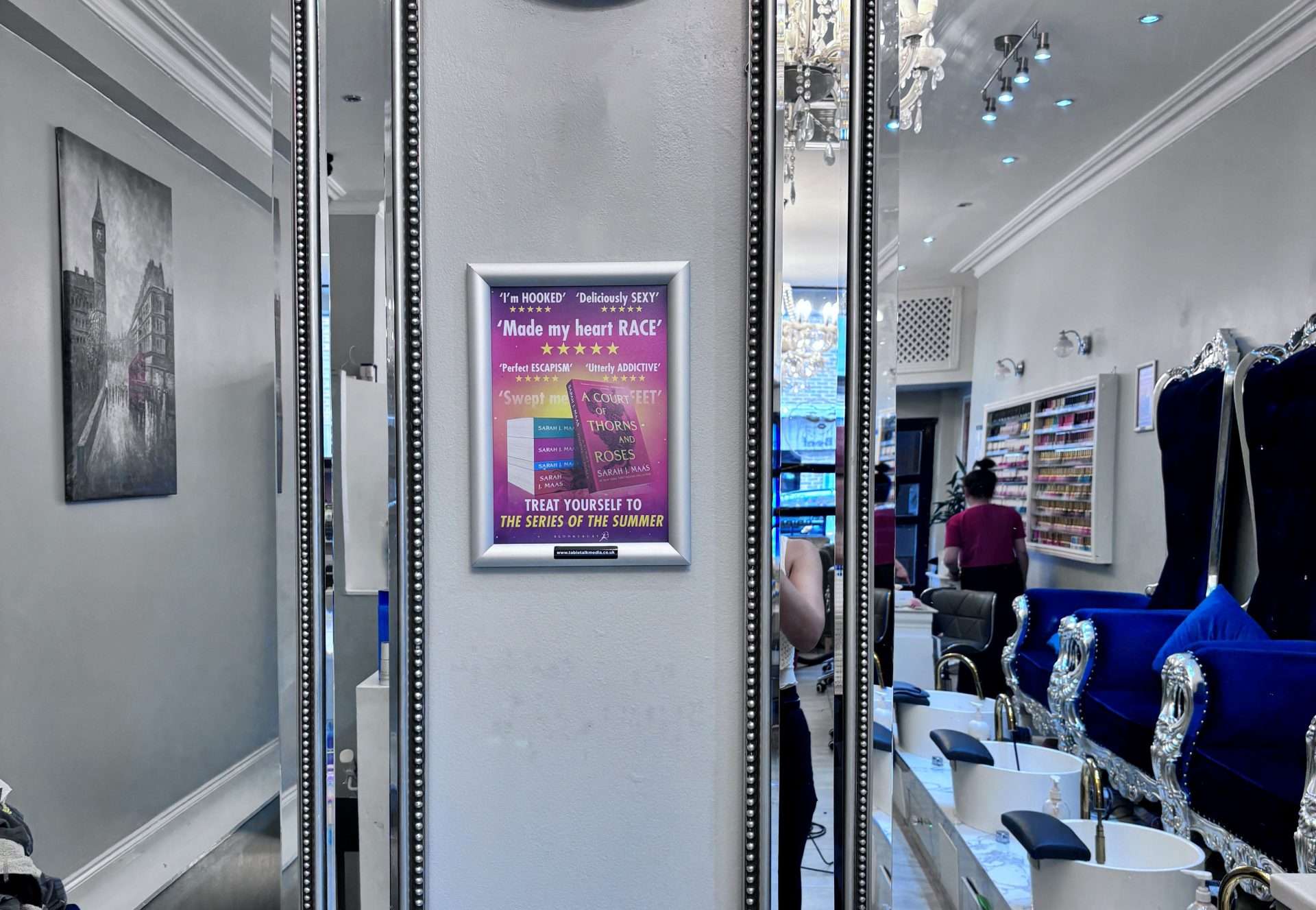 Framed Bloomsbury poster for Sarah J. Maas's A Court of Thorns and Roses series on a pillar in a London nail salon