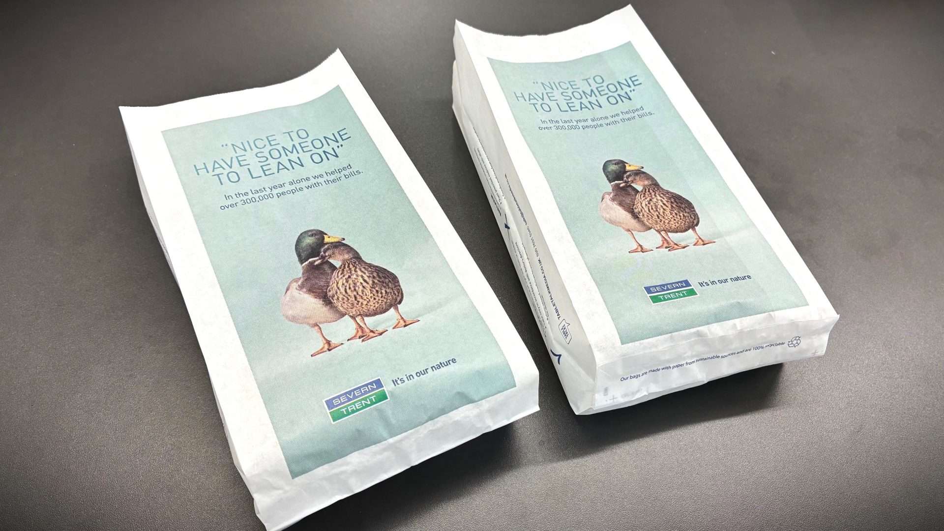 Two Severn Trent pharmacy bags showing a pair of ducks leaning on each other with the line 'Nice to have someone to lean on'
