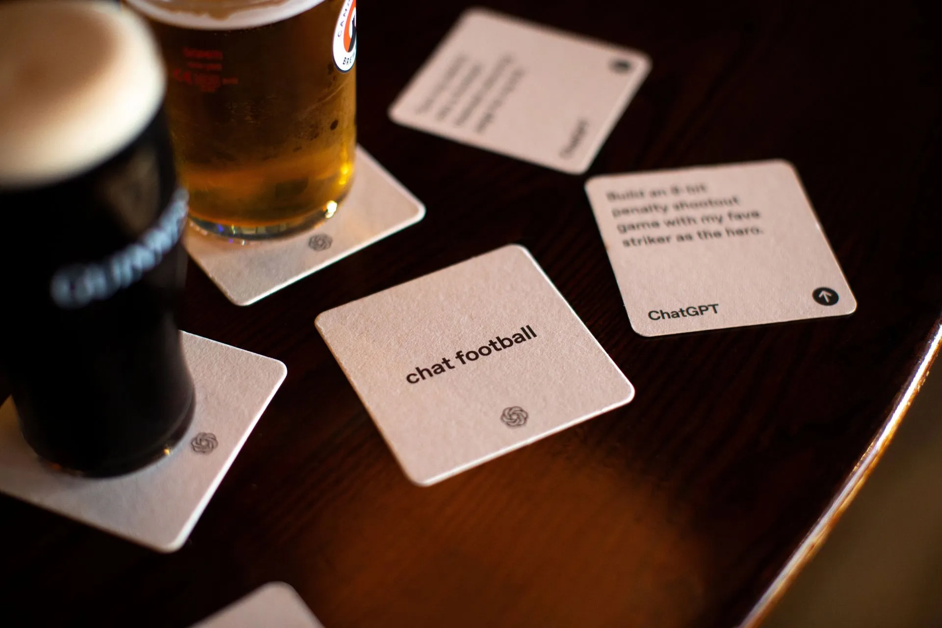 ChatGPT 'chat football' beer mats beside pints of lager and stout on a pub table