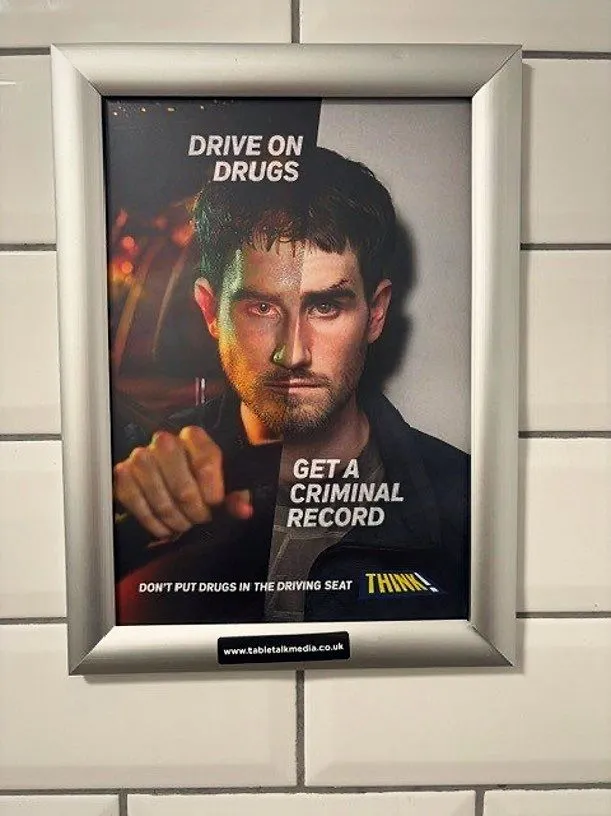 THINK! 'Drive on drugs, get a criminal record' poster in a framed washroom panel on a white-tiled wall