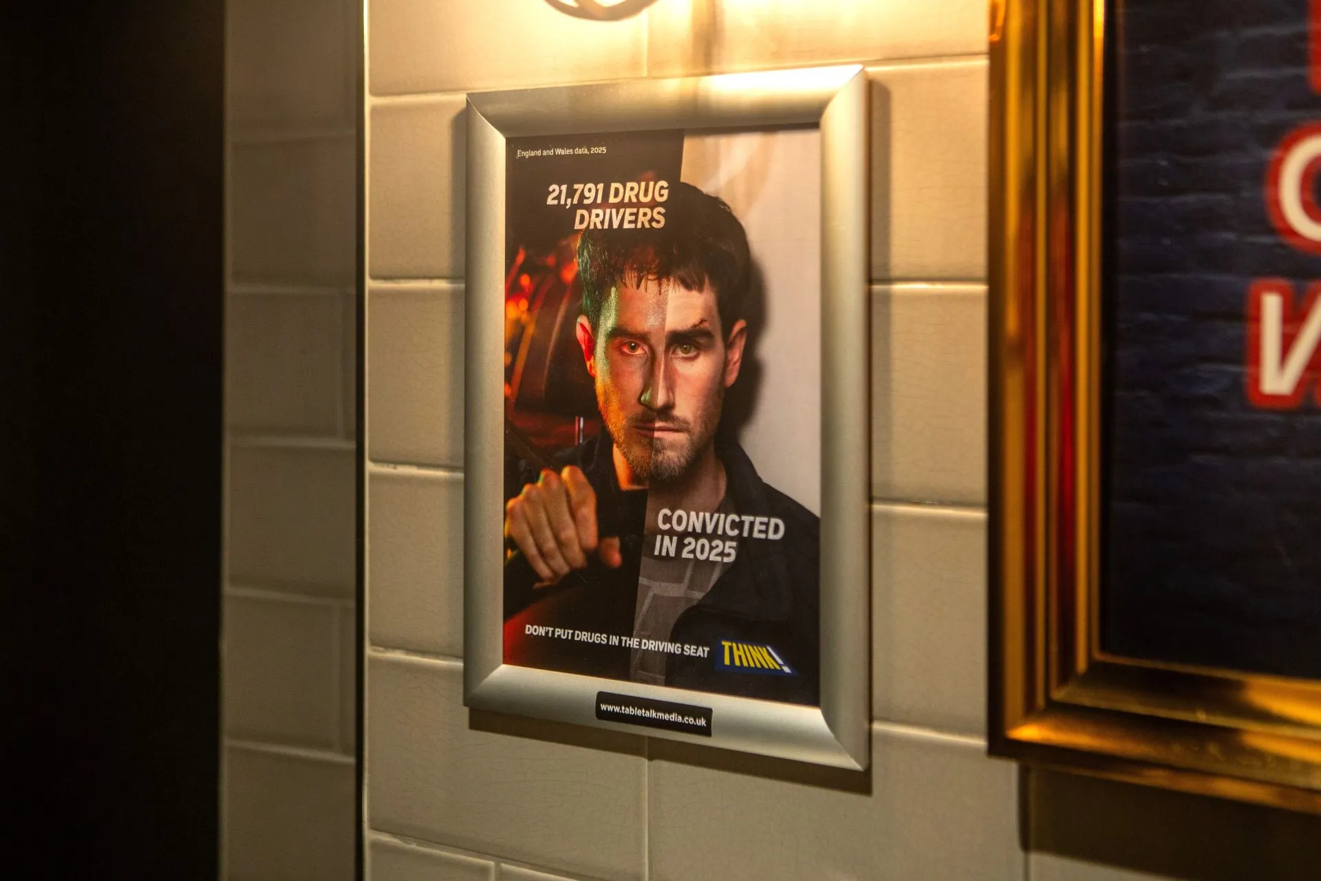 THINK! '21,791 drug drivers convicted in 2025' poster in a framed washroom panel on a tiled pub wall