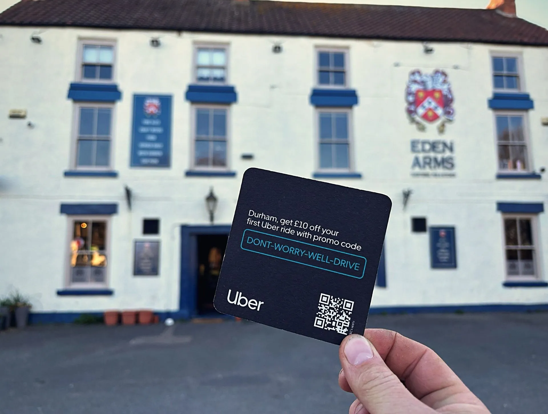 Hand holding an Uber Durham '£10 off your first ride' beer mat outside the Eden Arms pub