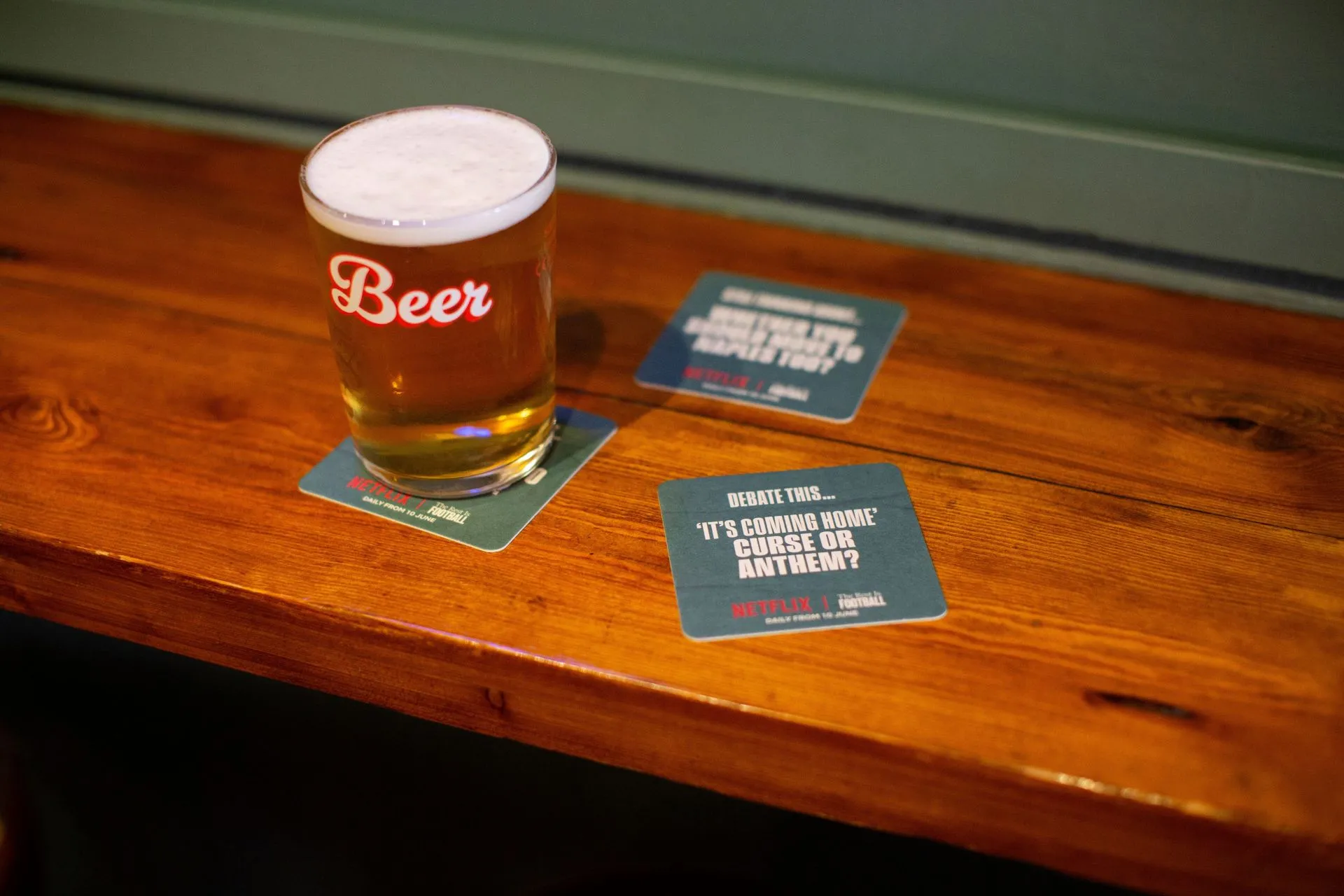 Netflix The Rest Is Football 'It's coming home' debate beer mats beside a pint on a pub bar