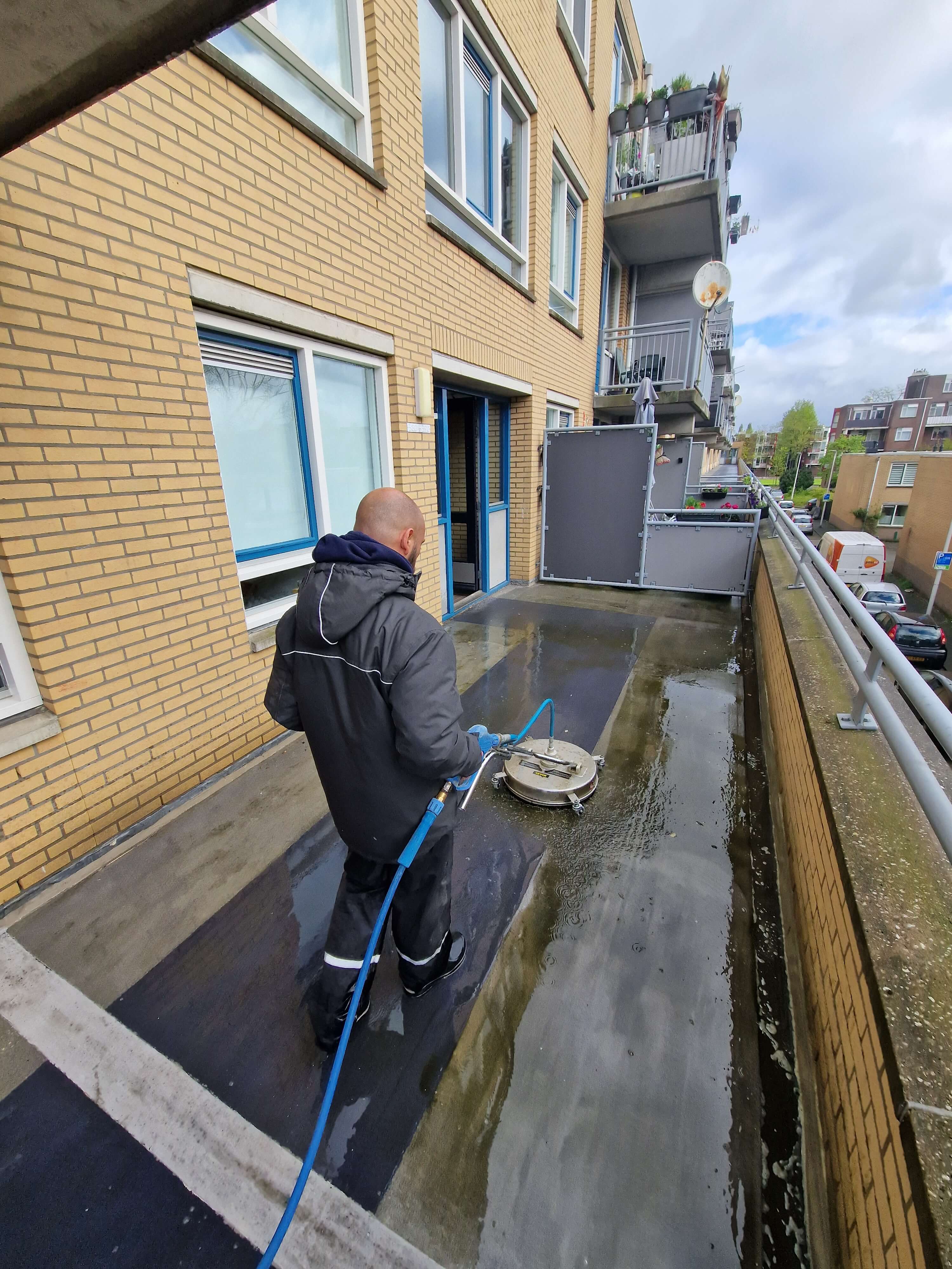 Van Klaveren reinigt een galerijvloer aan de Boezemstraat in Rotterdam.