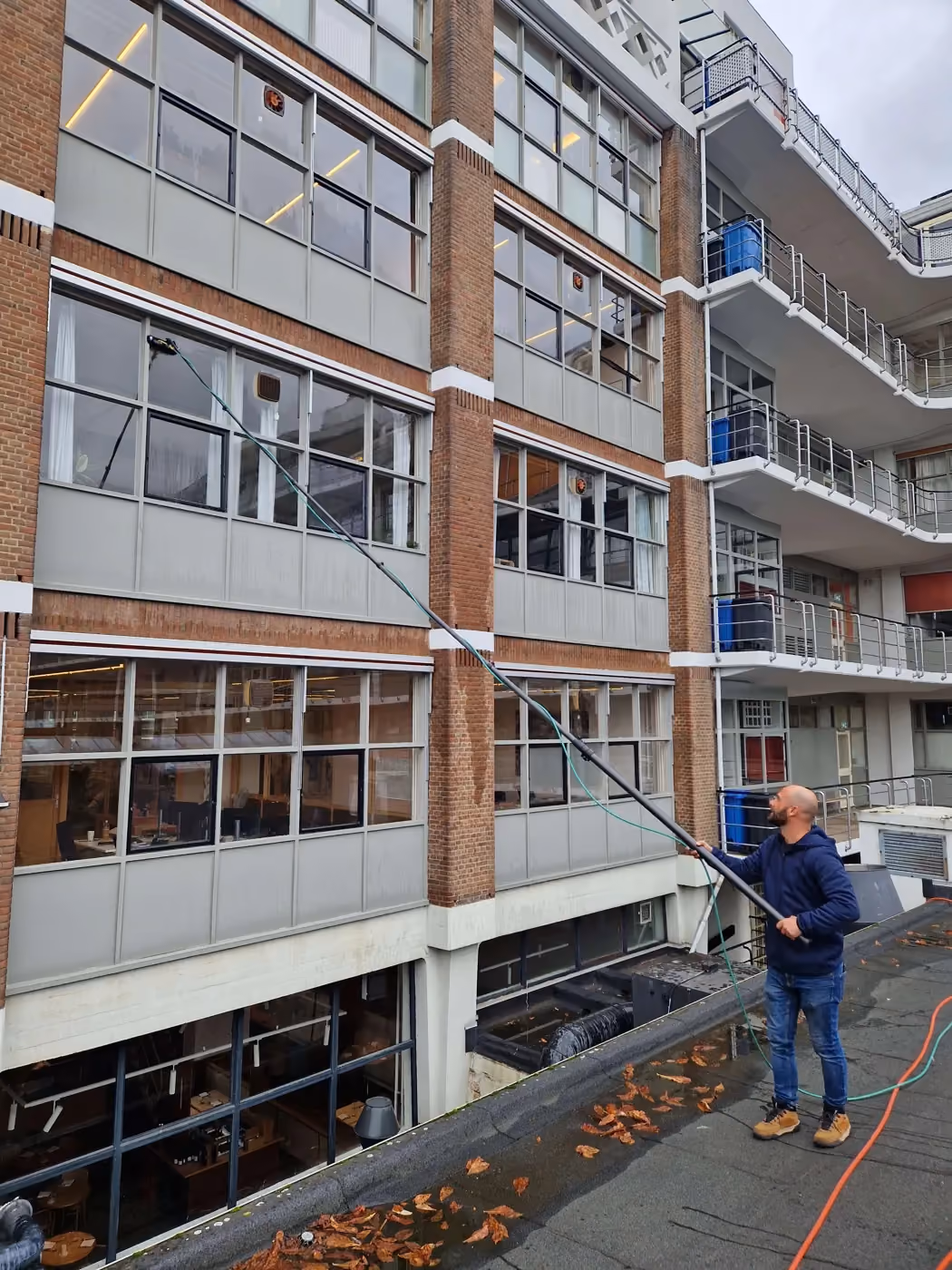 Glasbewassing met een tuckerborstel en osmosewater door Van Klaveren bij HIG, Goudsesingel in Rotterdam.
