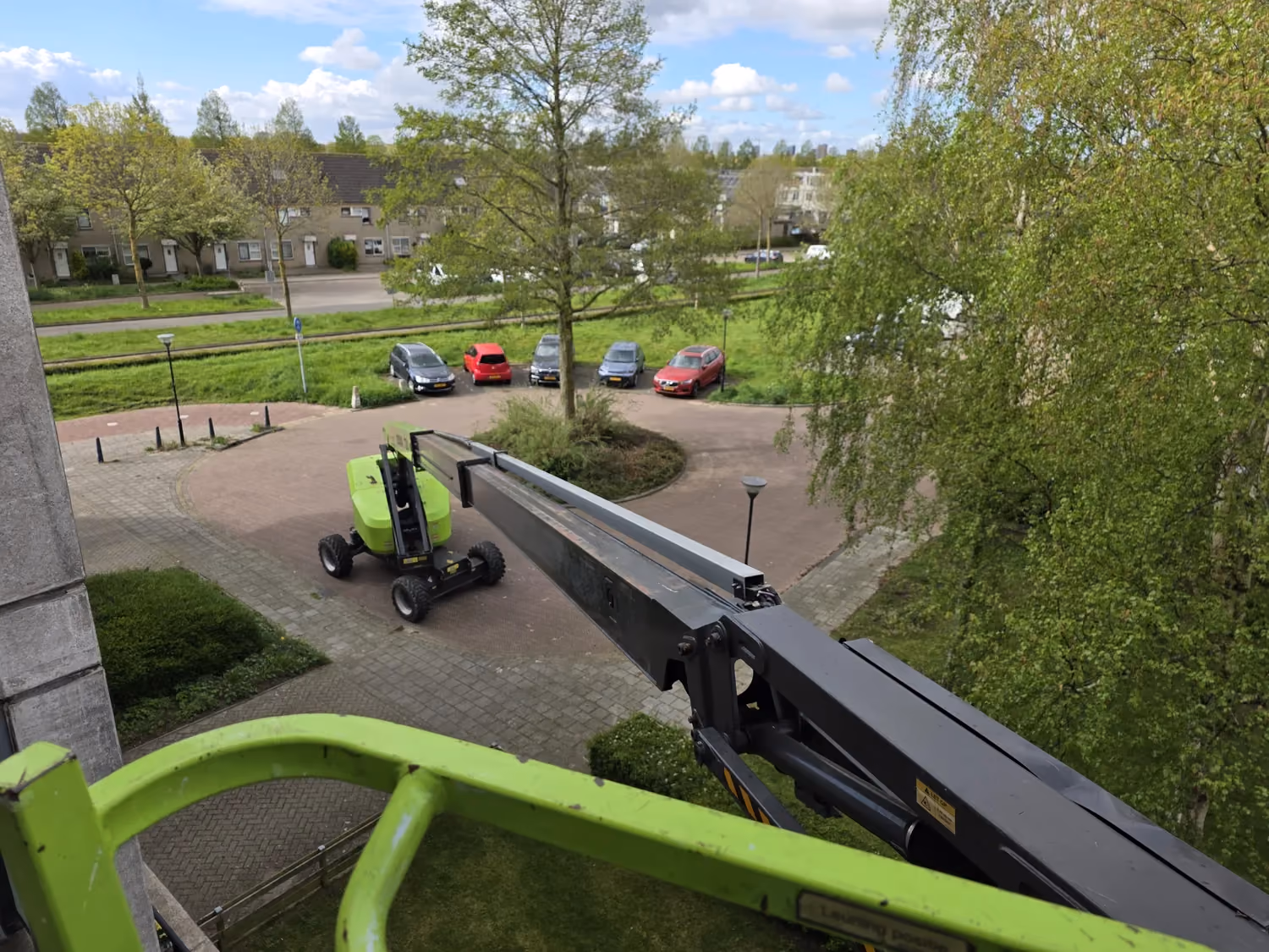 Zicht vanuit de werkbak van een hoogwerker bij werkzaamheden aan een gebouw.