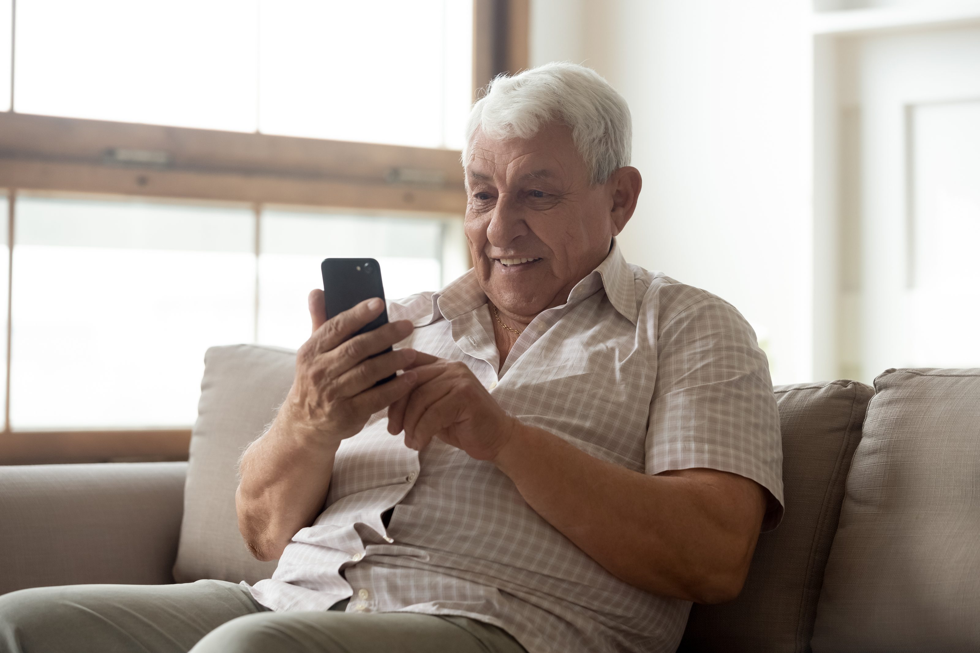 A man checking his phone at home, the way most people first reach Pioneer Research