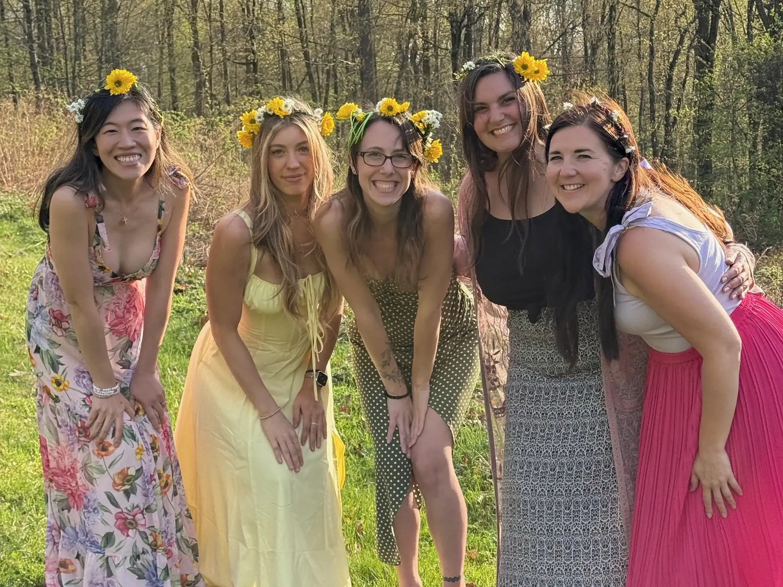 Amanda and four friends in flower crowns laughing together in a spring field